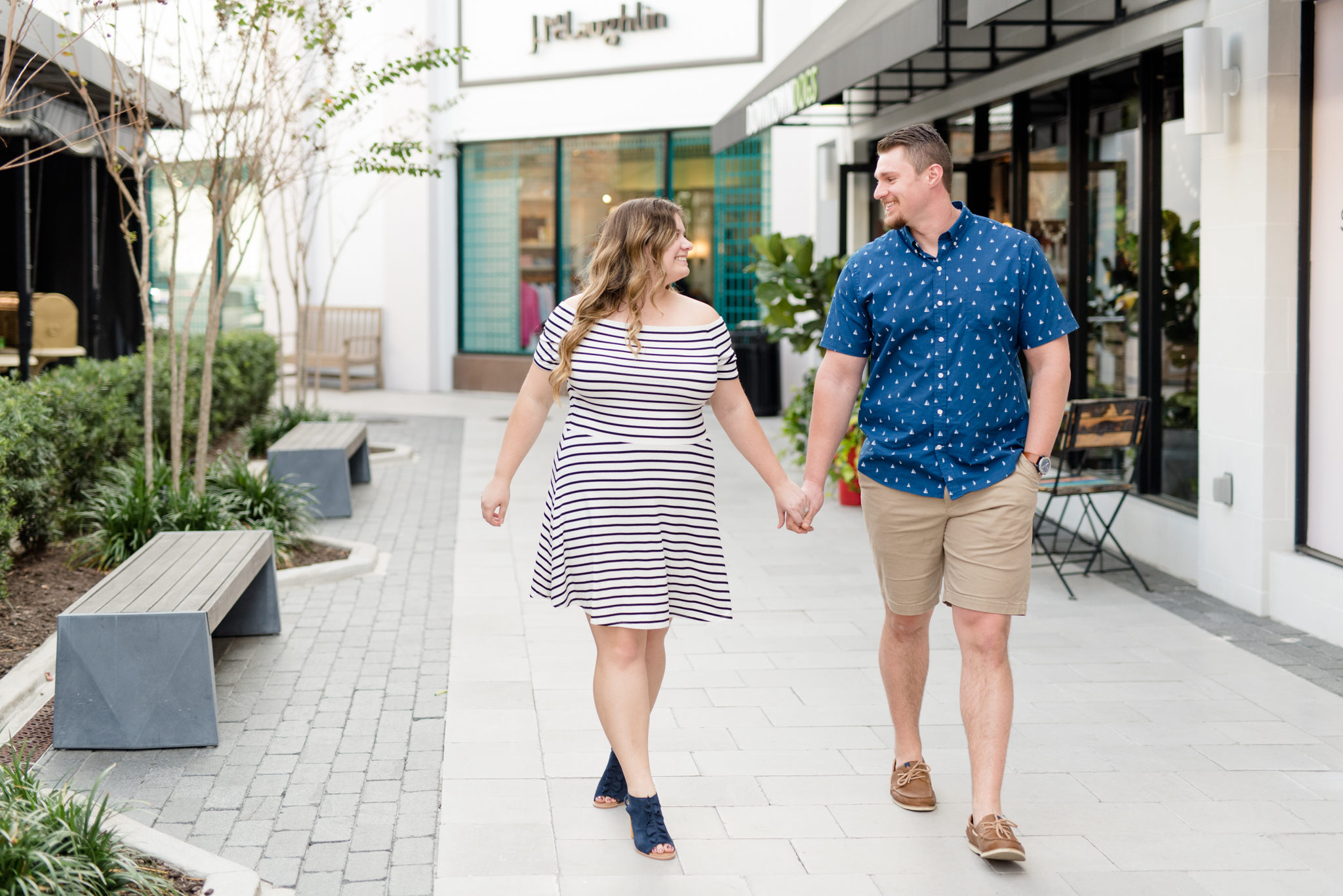 Couple walks along urban shops.