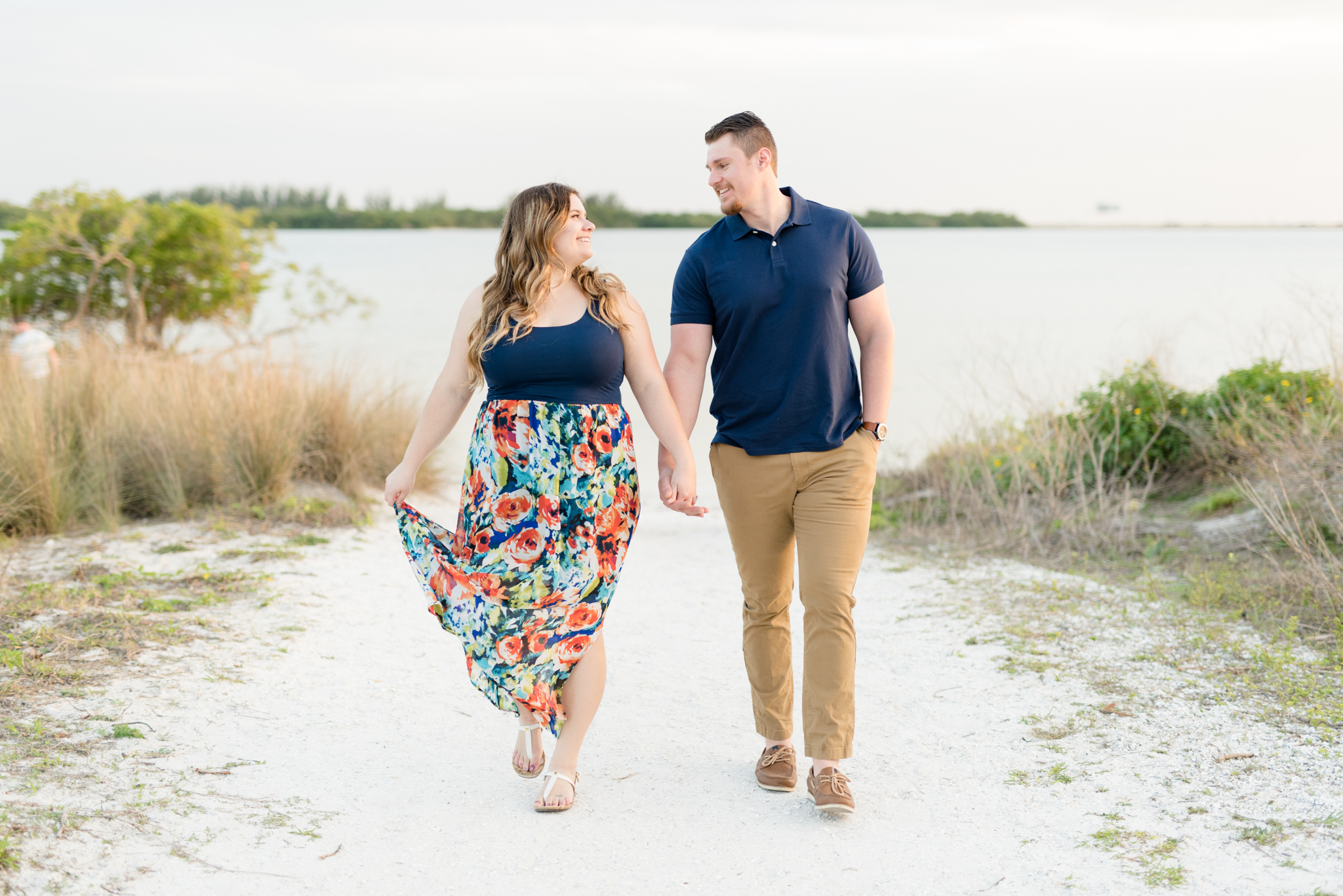 Couple walks and laughs on beach path.