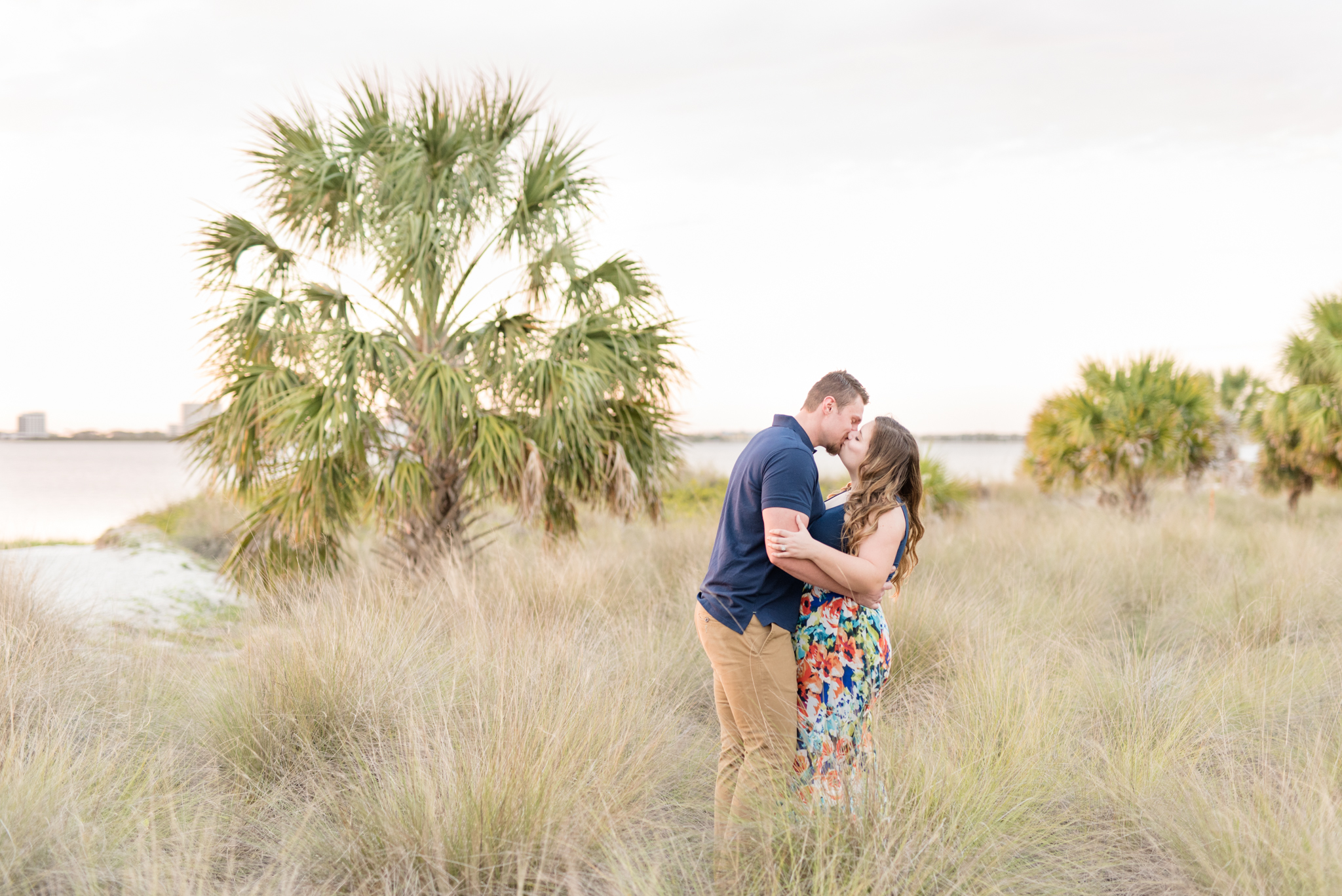 Couple kisses in tall beach grass.