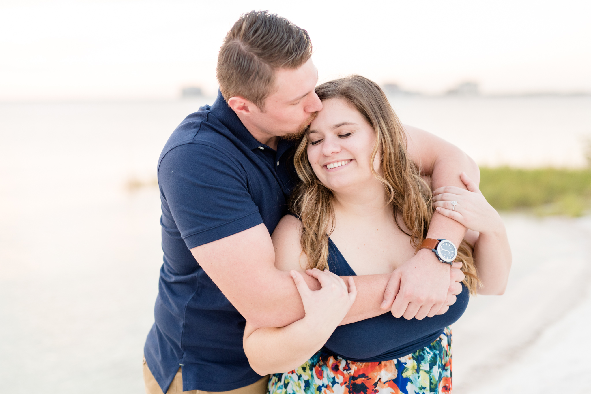 Couple snuggles and laughs on beach.