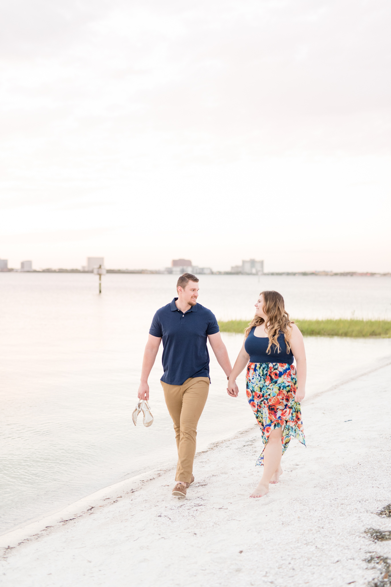 Couples walks hand in hand on beach.
