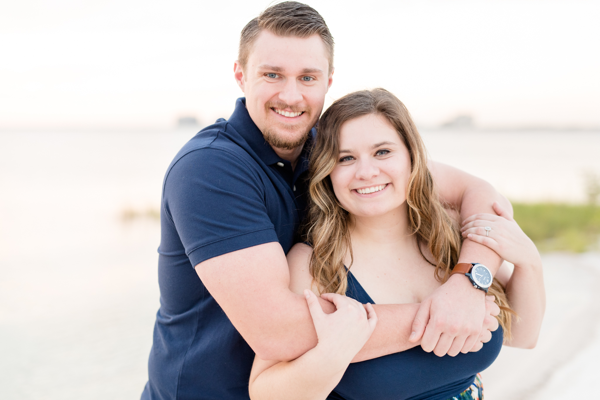 Couple snuggles and smiles at camera.