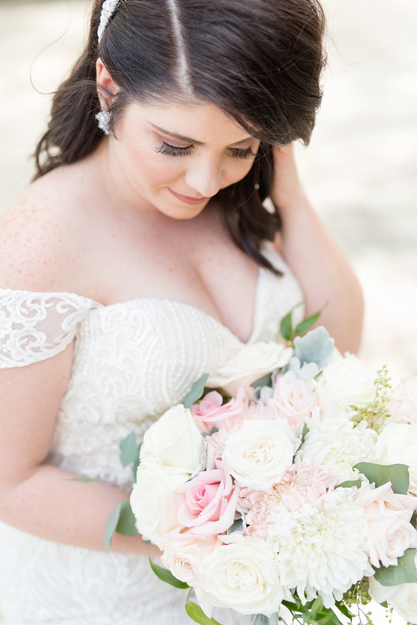 Bride looks down at flowers.