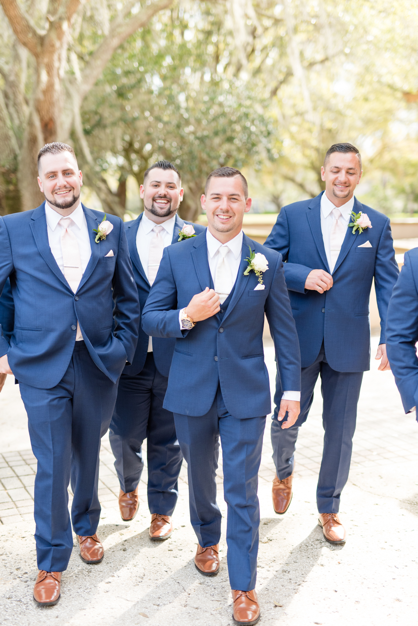 Groom and attendants walk and smile.