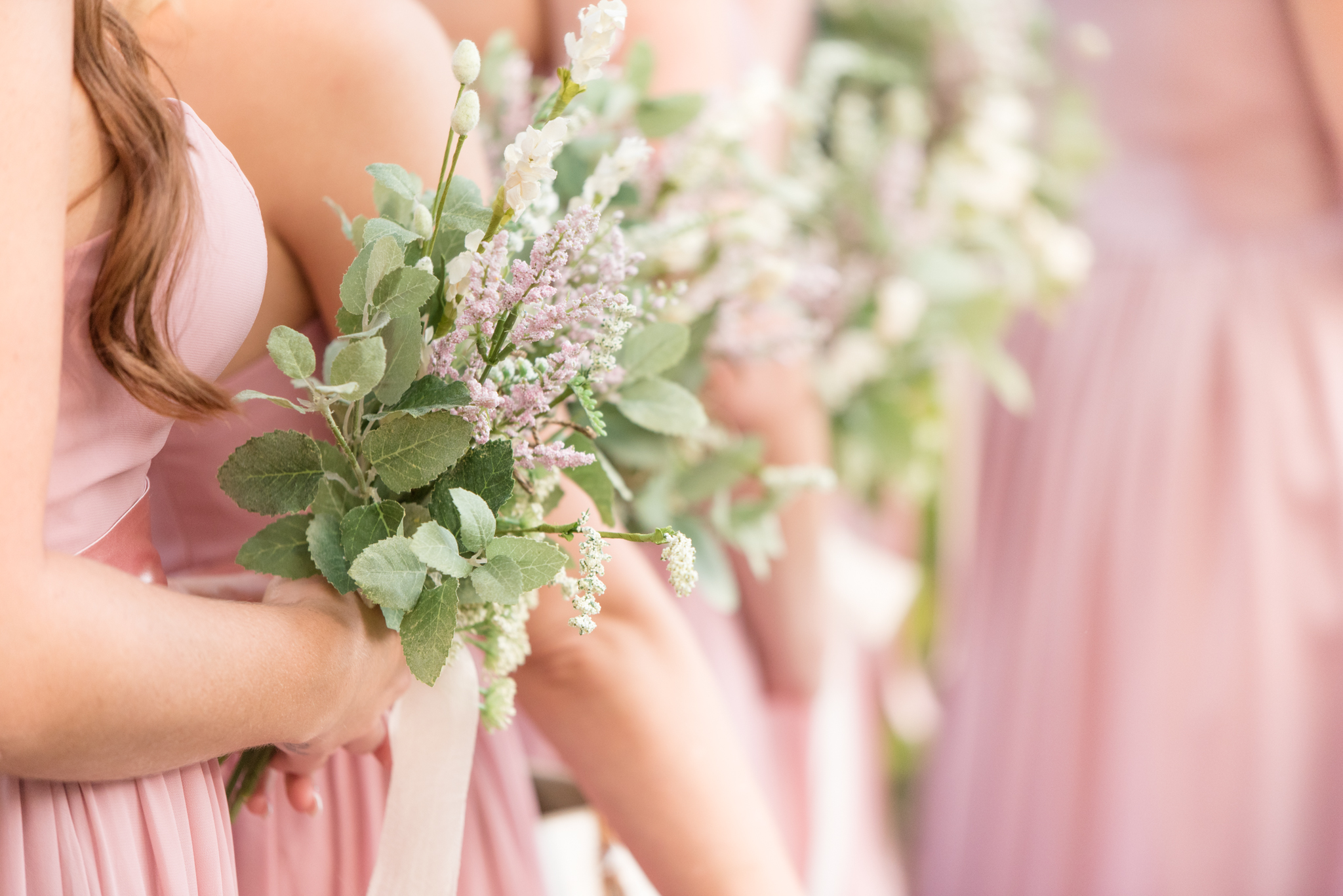 Bridesmaids hold flowers during ceremony.