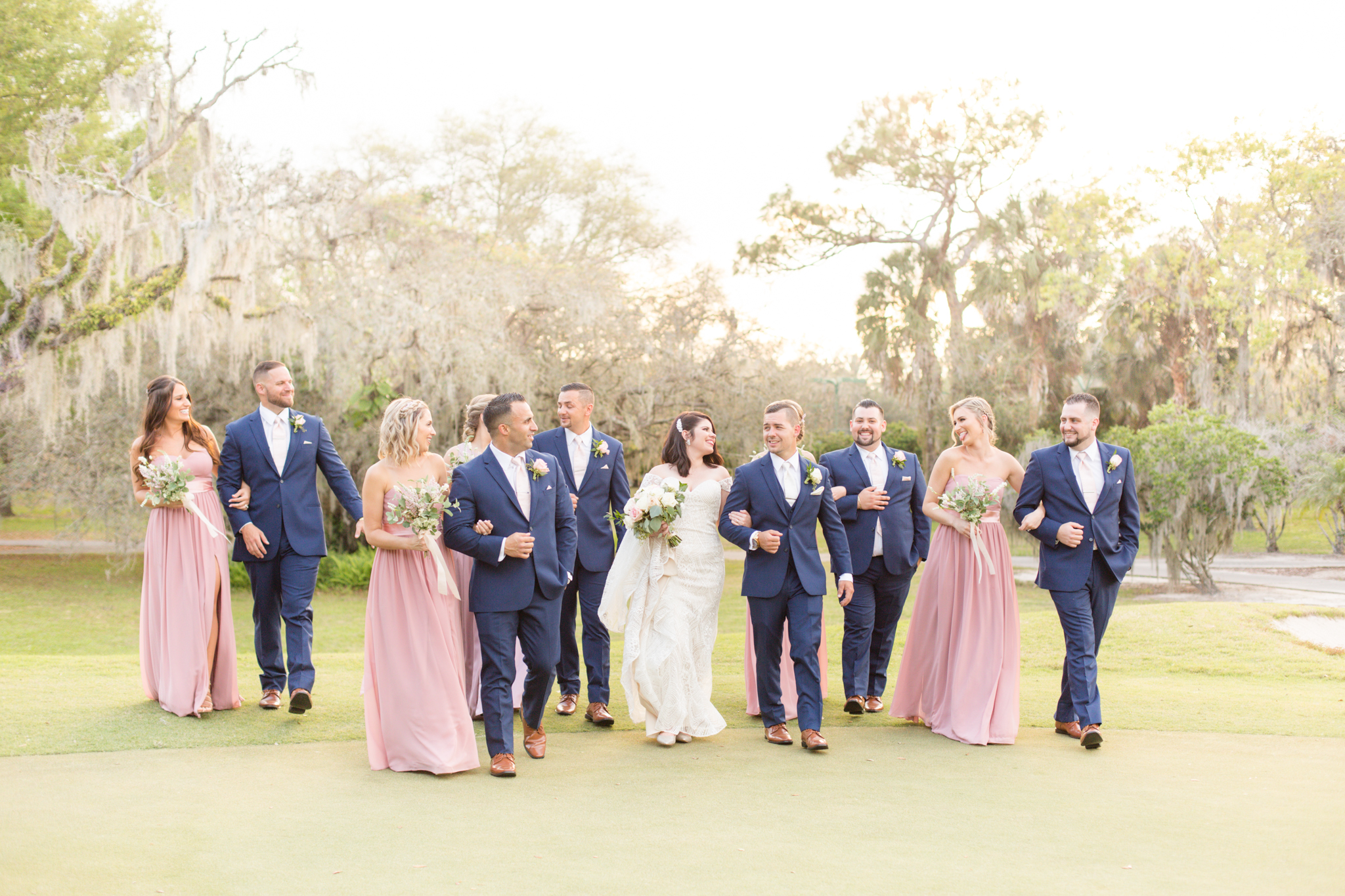 Wedding party walks and laughs during sunset.
