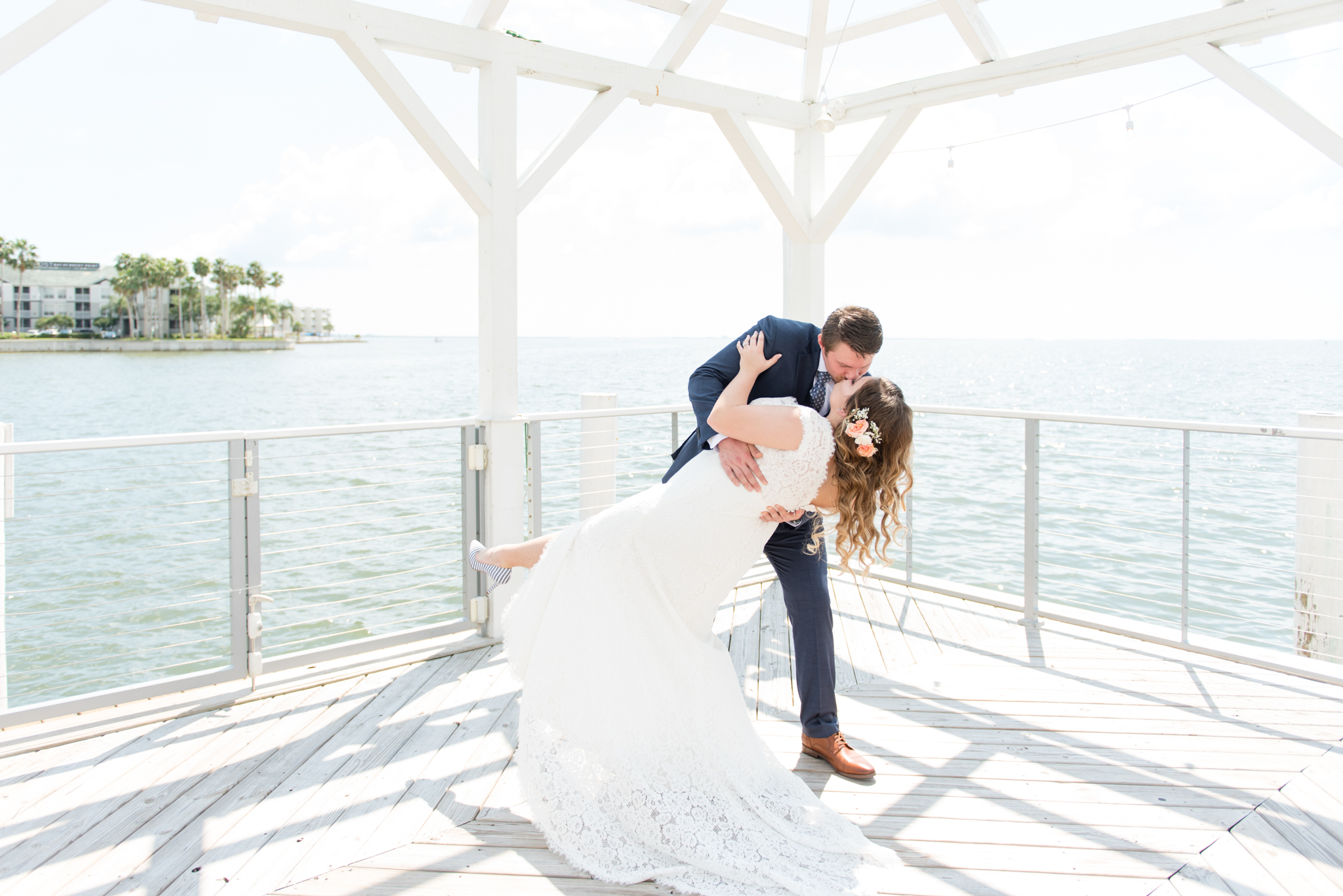 Groom dips bride on waterfront.