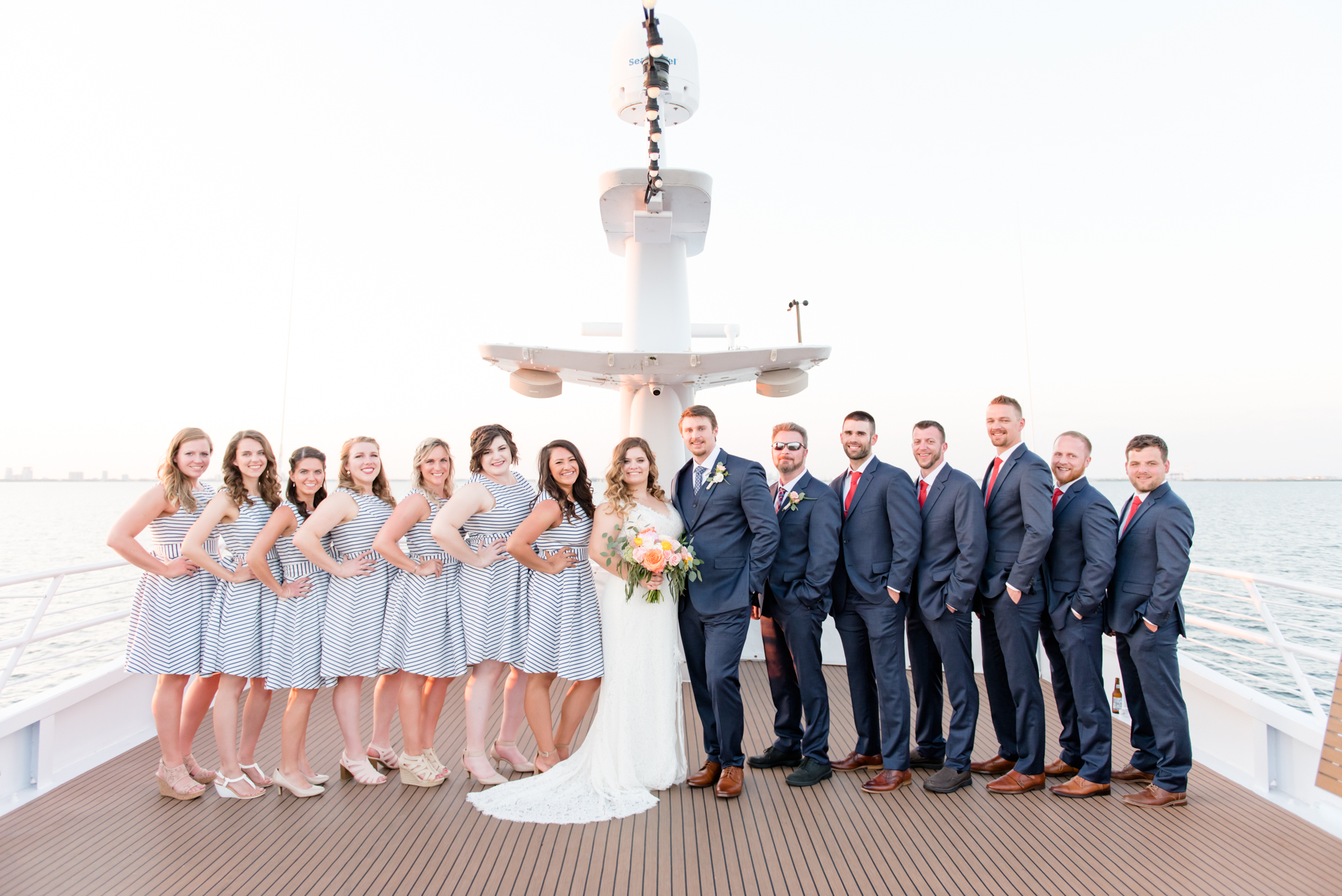 Wedding party smiles at camera on yacht.