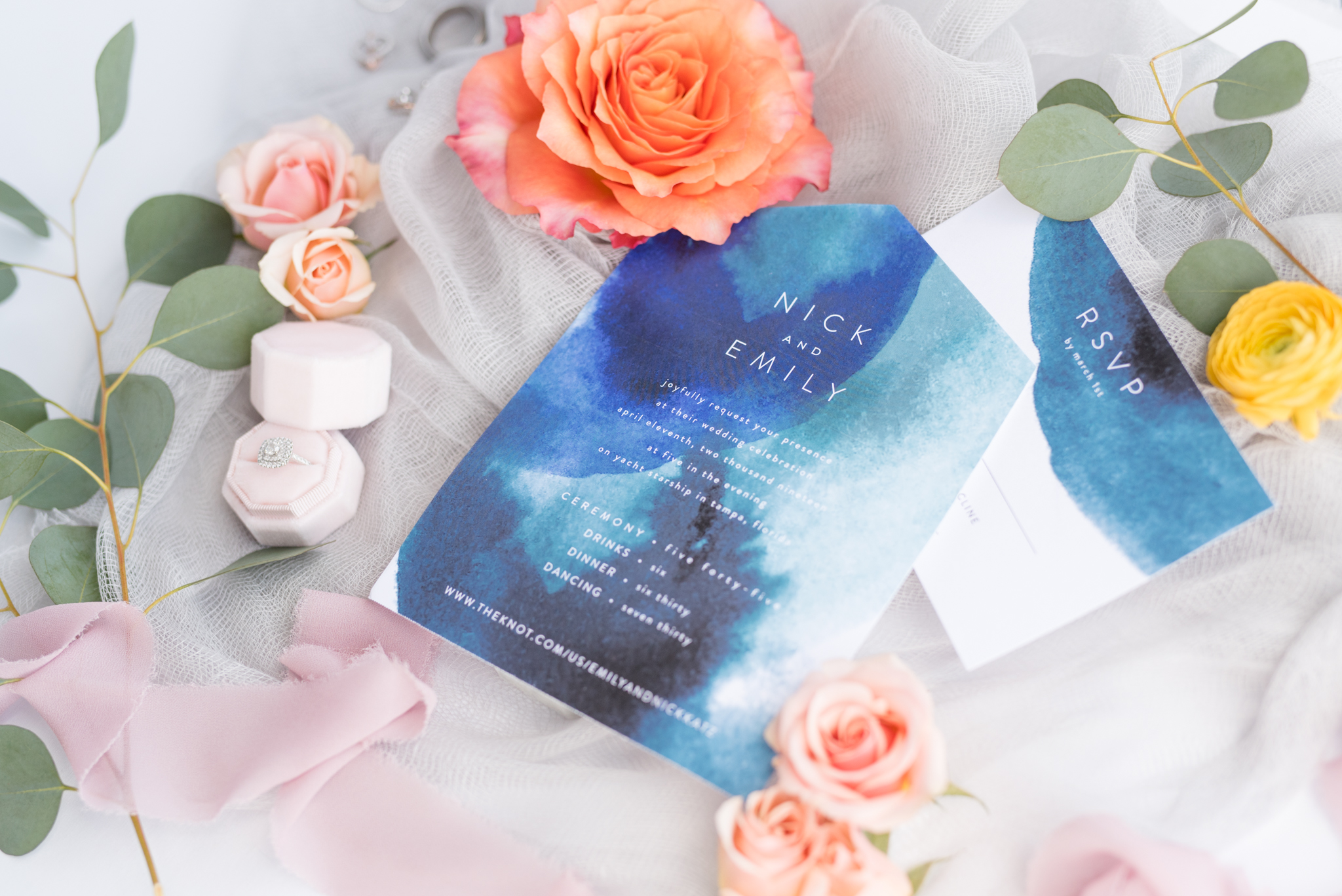 Watercolor wedding invitation sits with flowers.