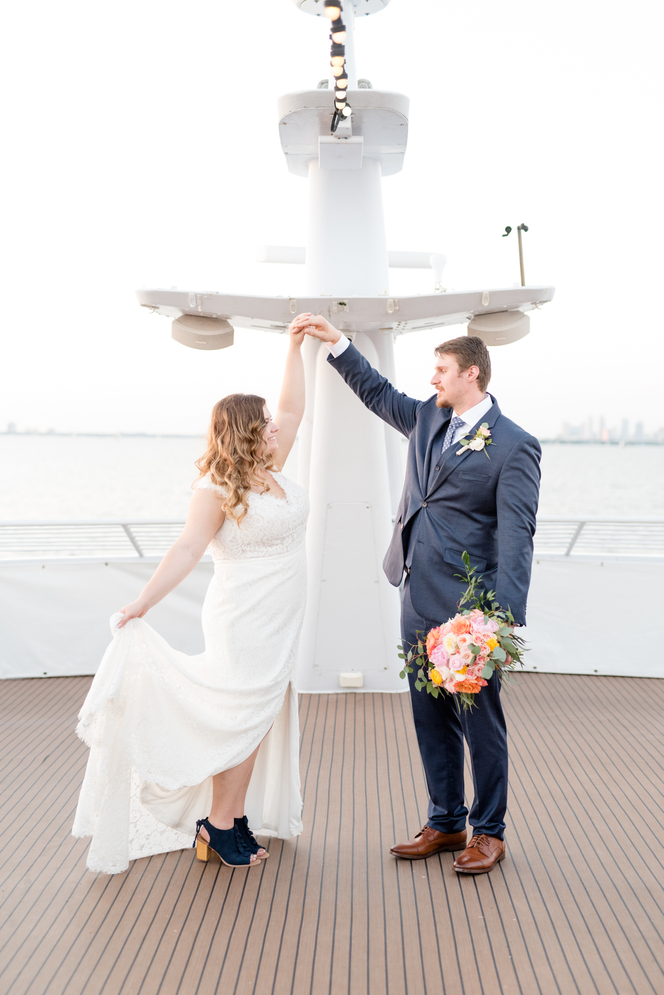 Groom twirls bride on yacht.