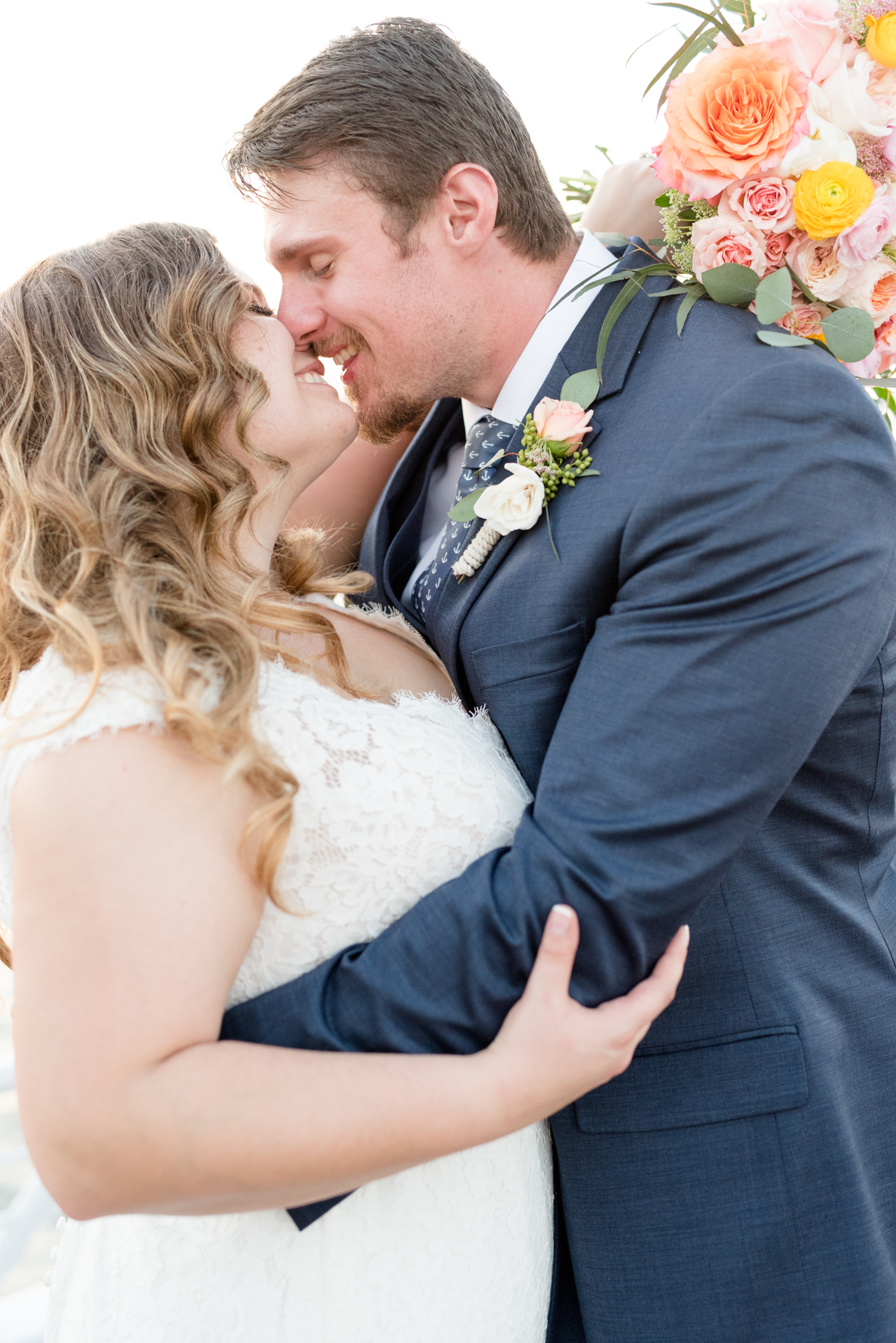 Bride and groom giggle as they go in for a kiss.