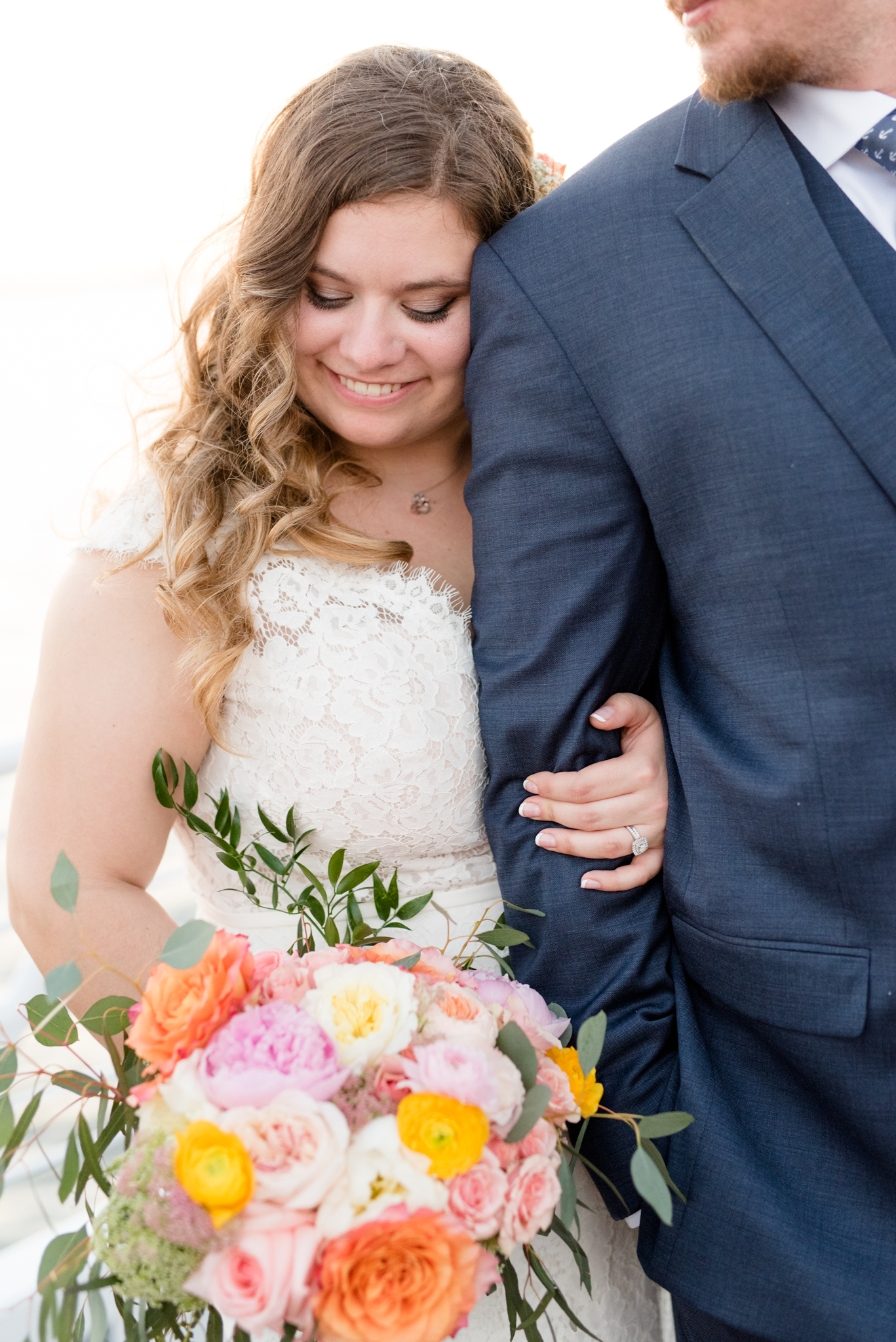 Bride looks down while snuggling groom.