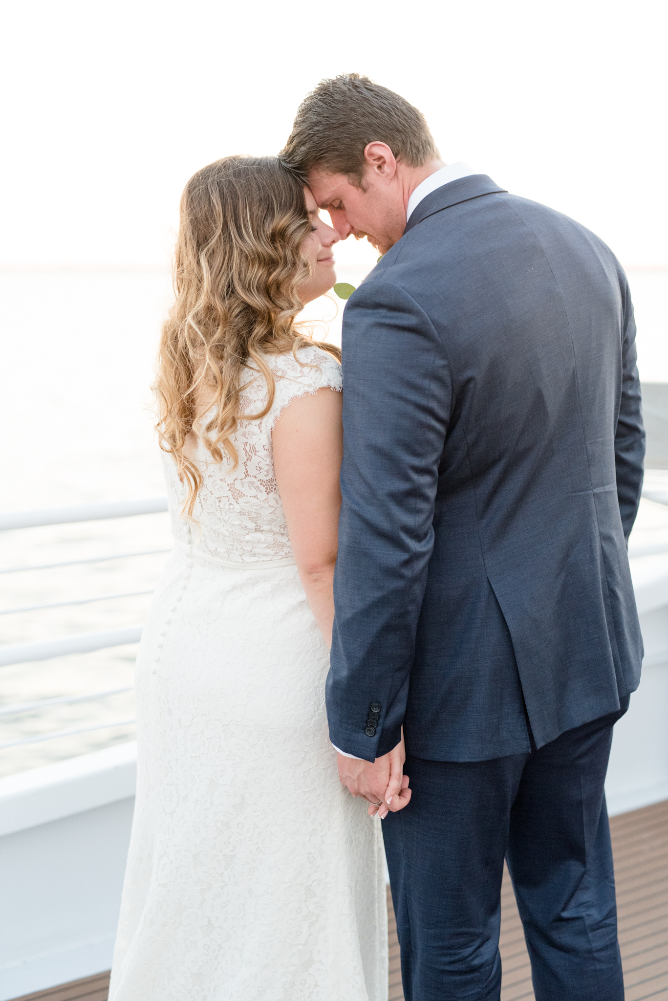Bride and groom snuggle on deck of yacht.