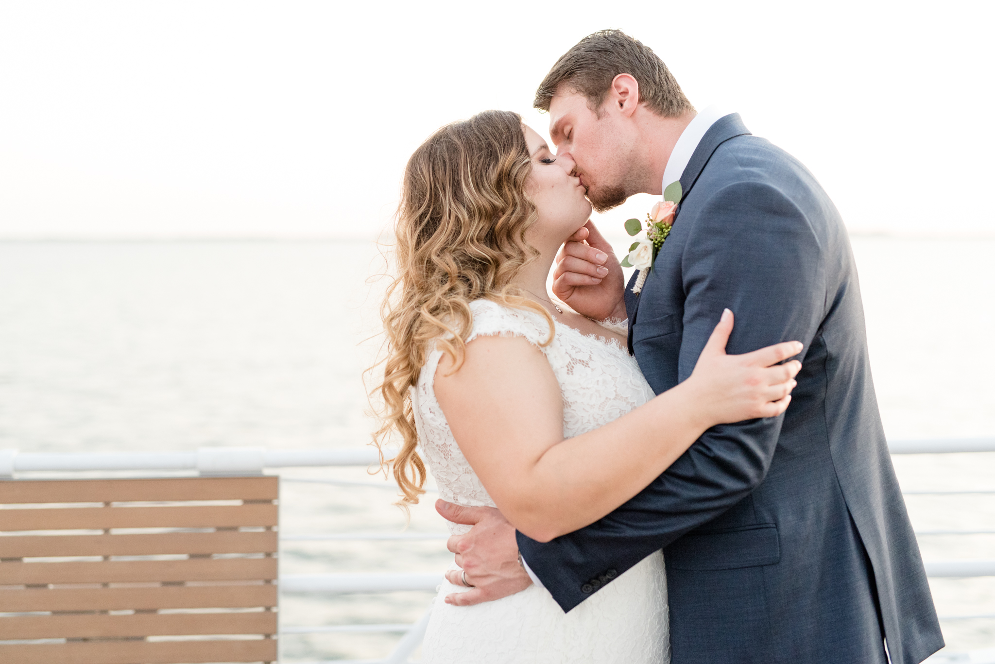 Groom pulls bride in for kiss on yacht.