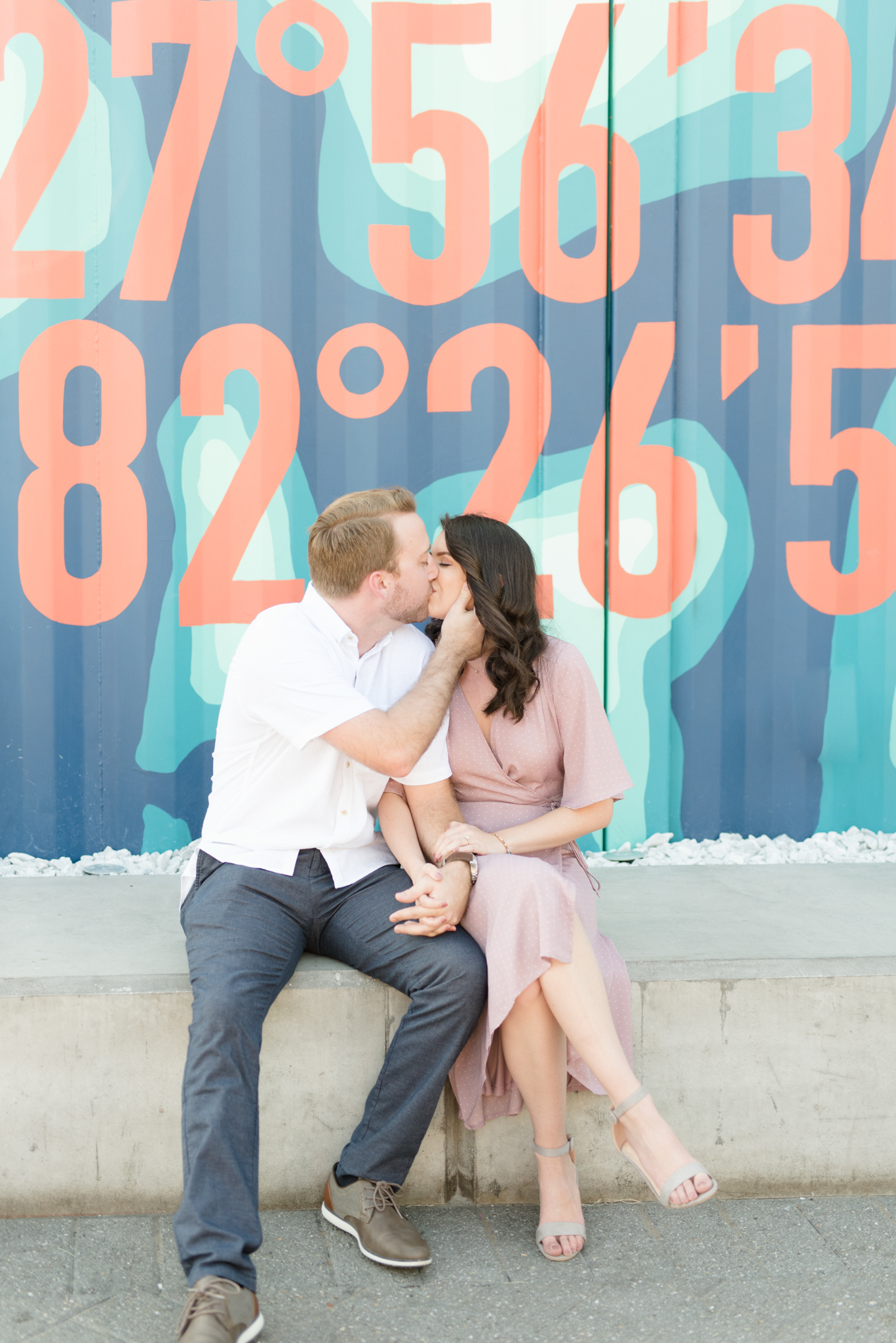 Couple kisses in front of mural.
