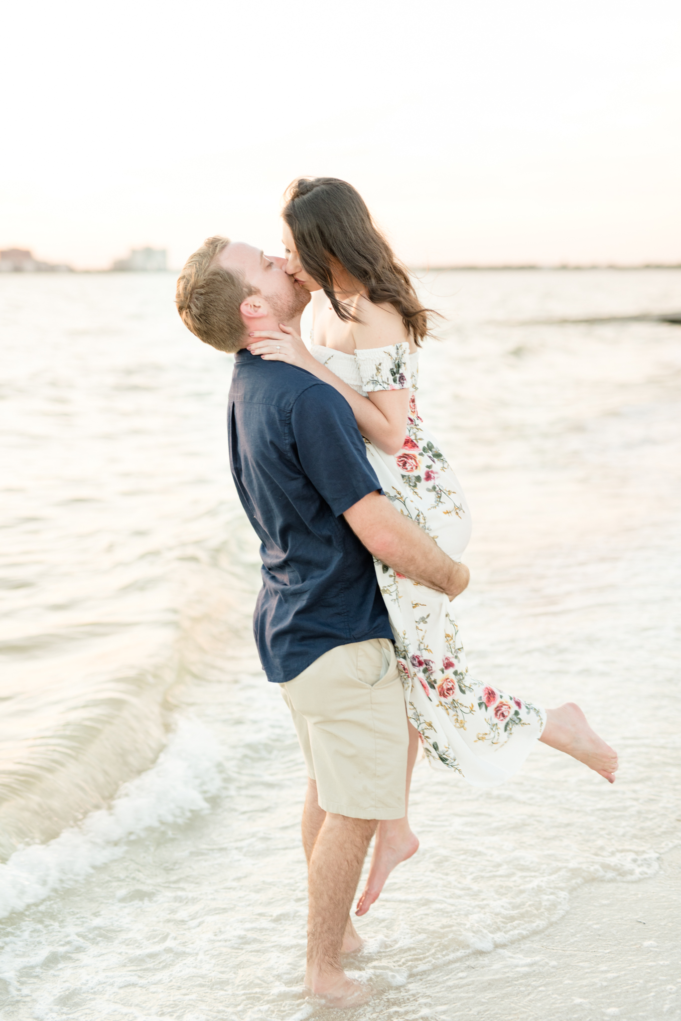 Groom stands in ocean and lifts fiance.