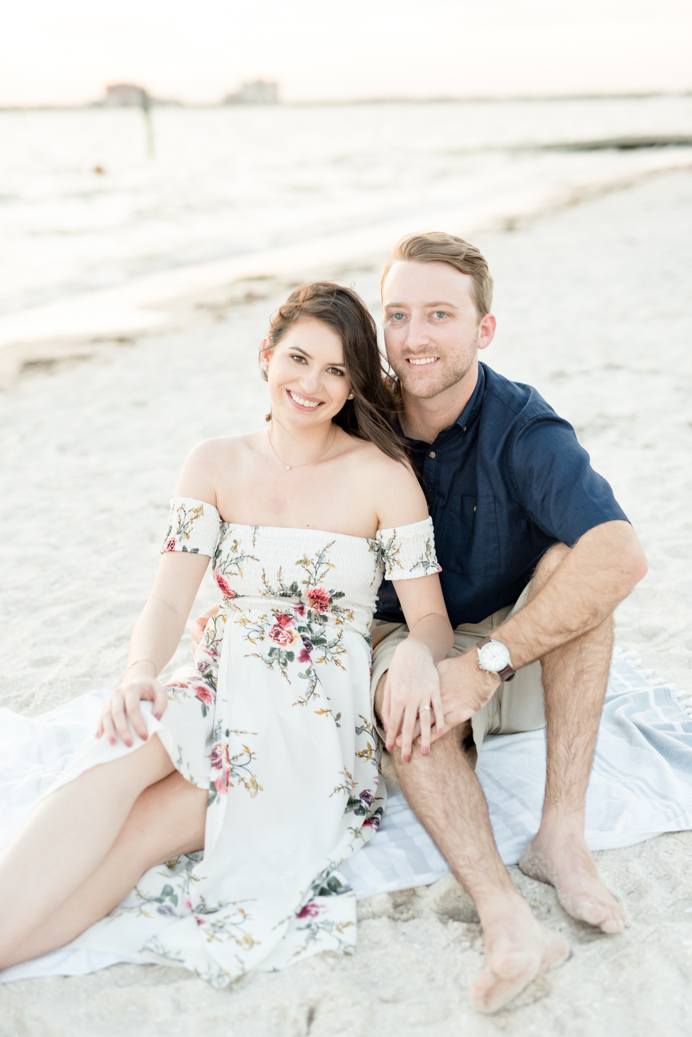 Couple sits on beach and smiles.