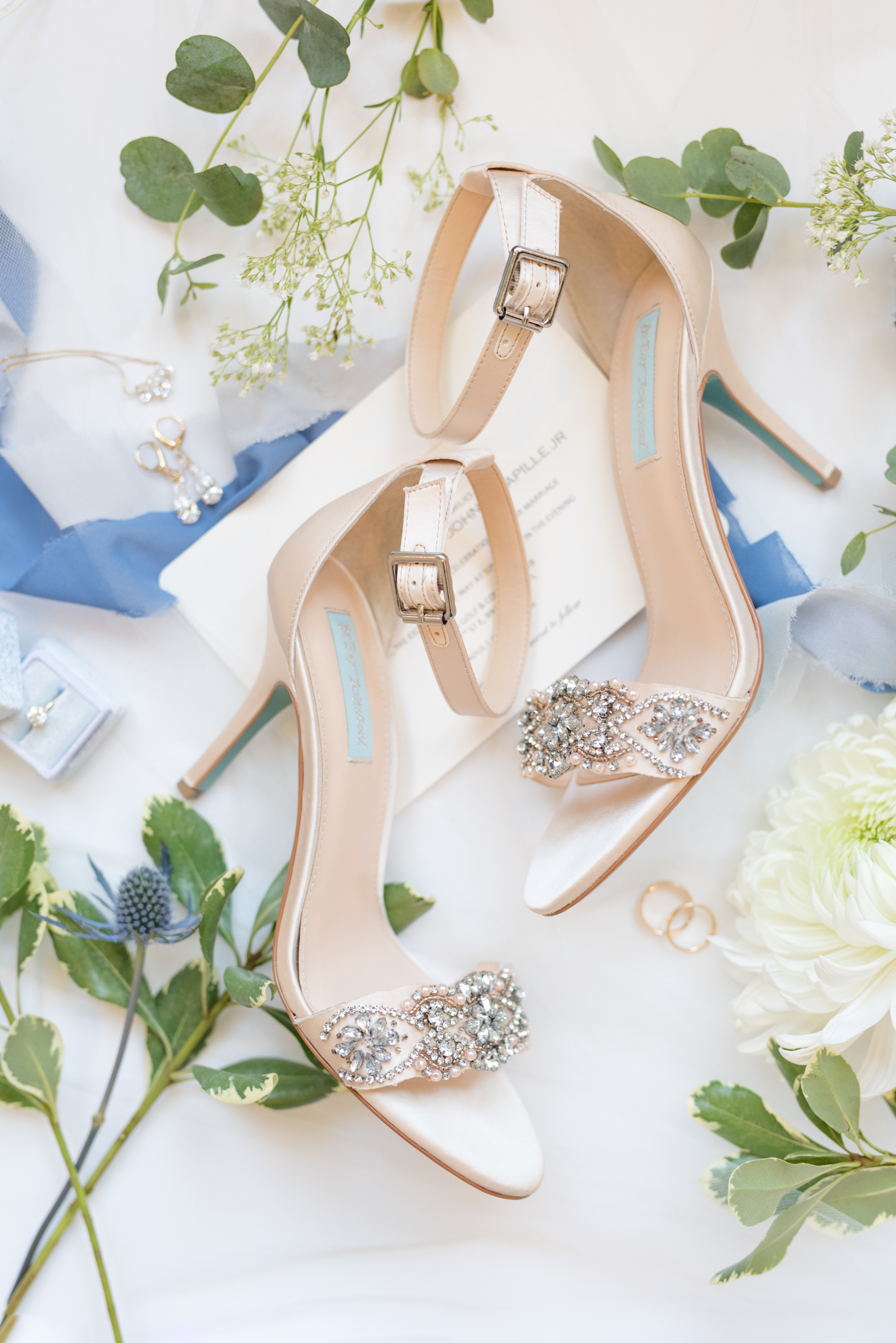 Wedding shoes sit on invitation suite.