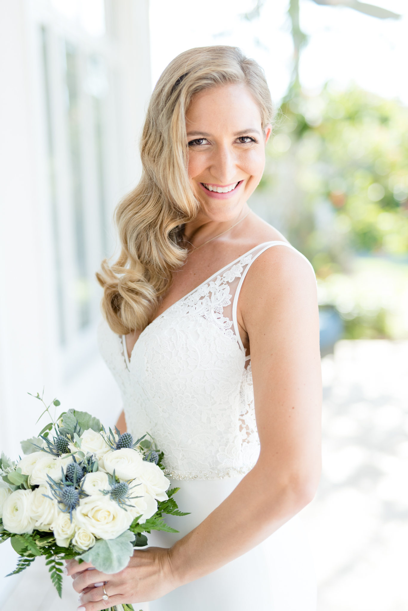 Bride holds flowers and smiles at camera.