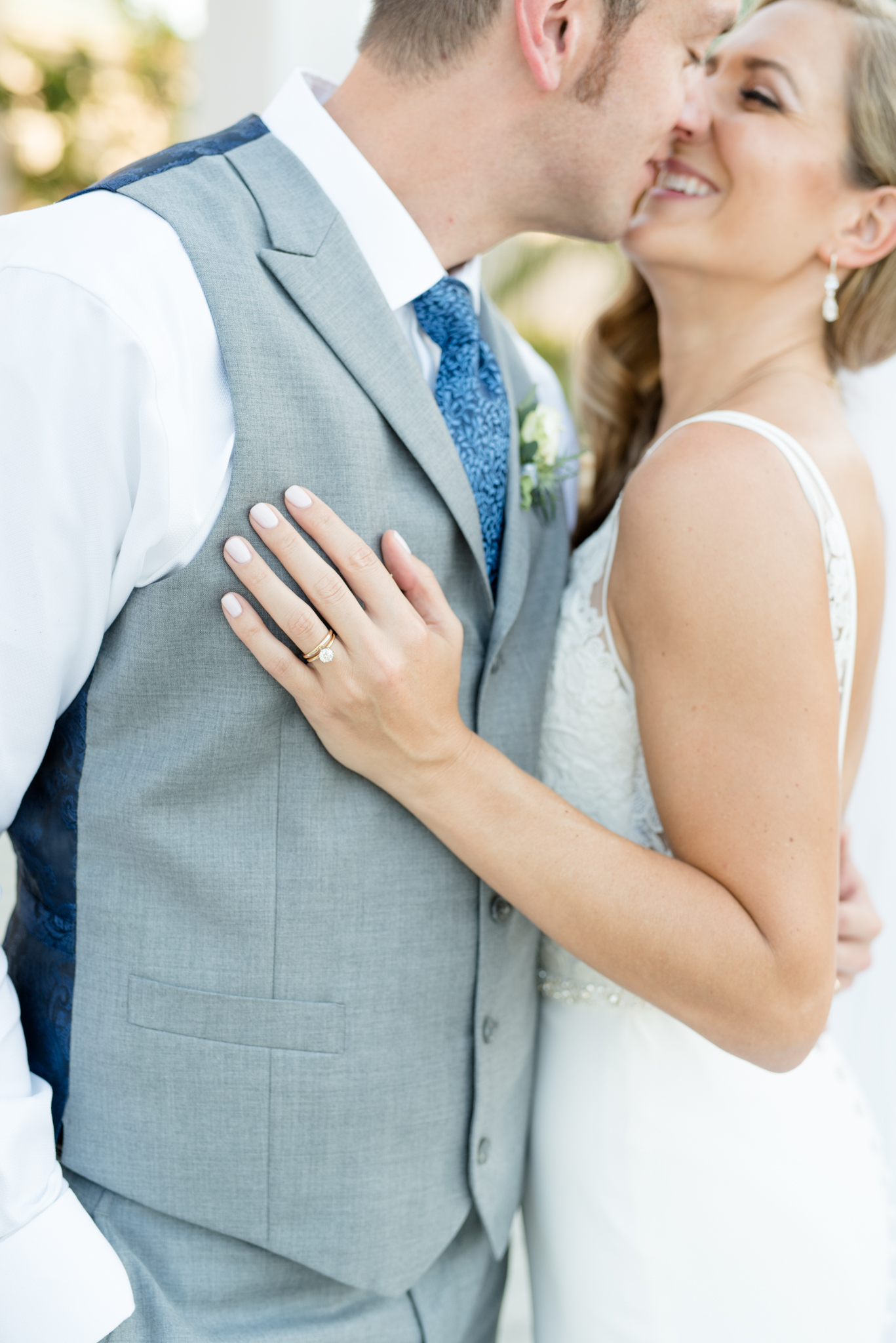 Closeup on wedding ring while wedding couple kiss.