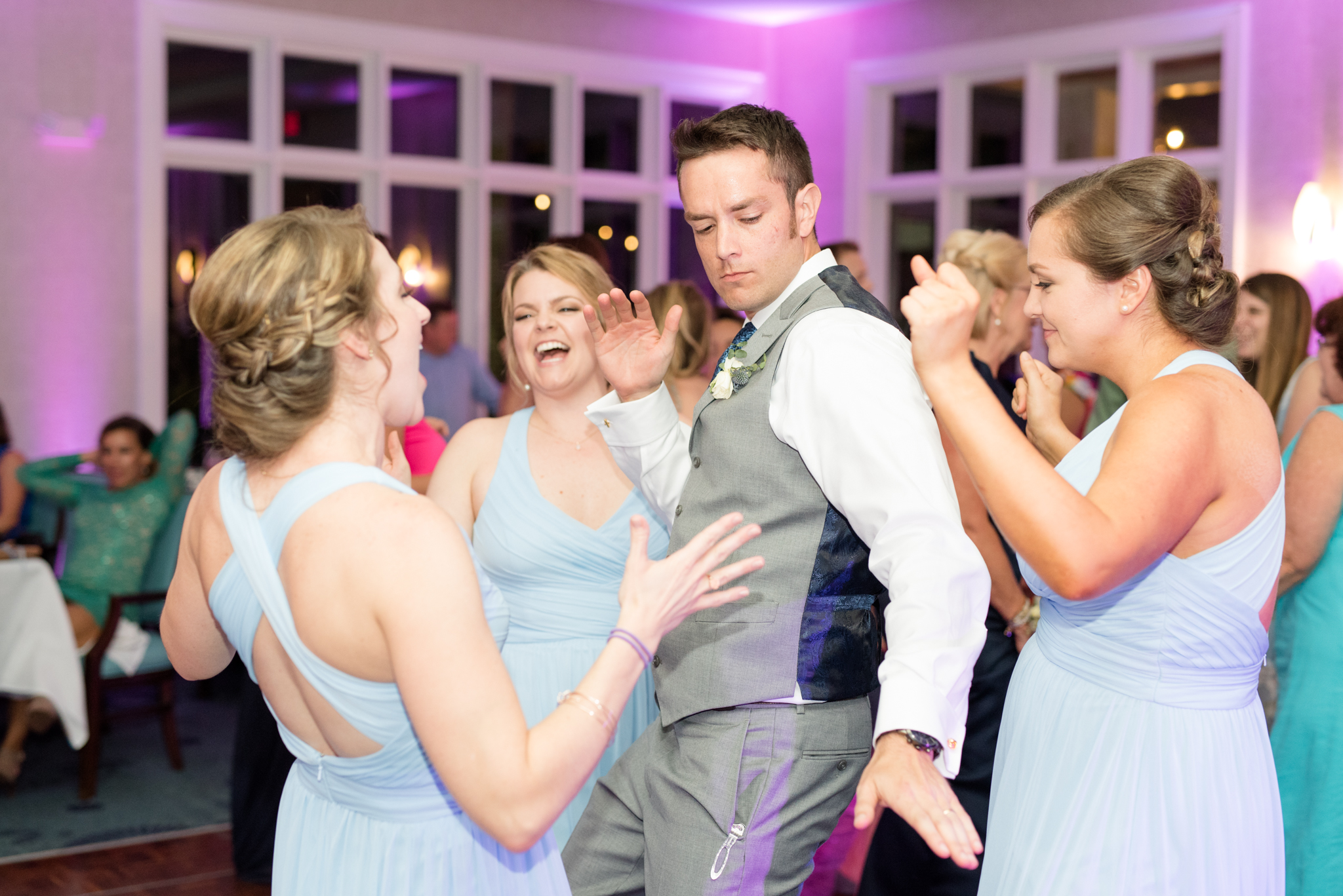 Groom and bridesmaids dance together.