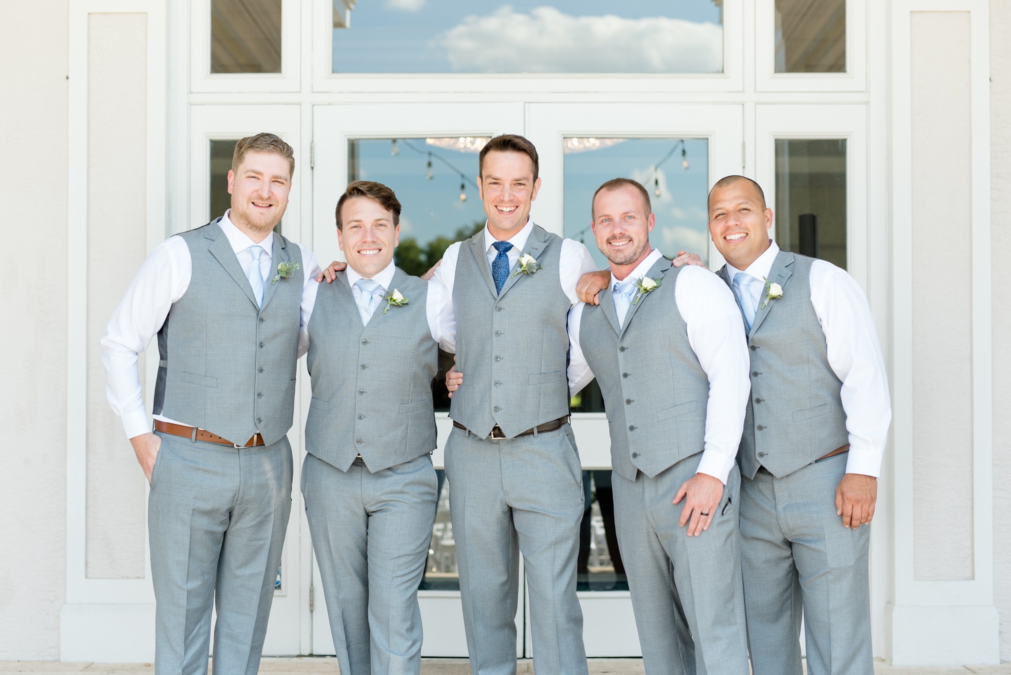 Groom and groomsmen smile at camera.