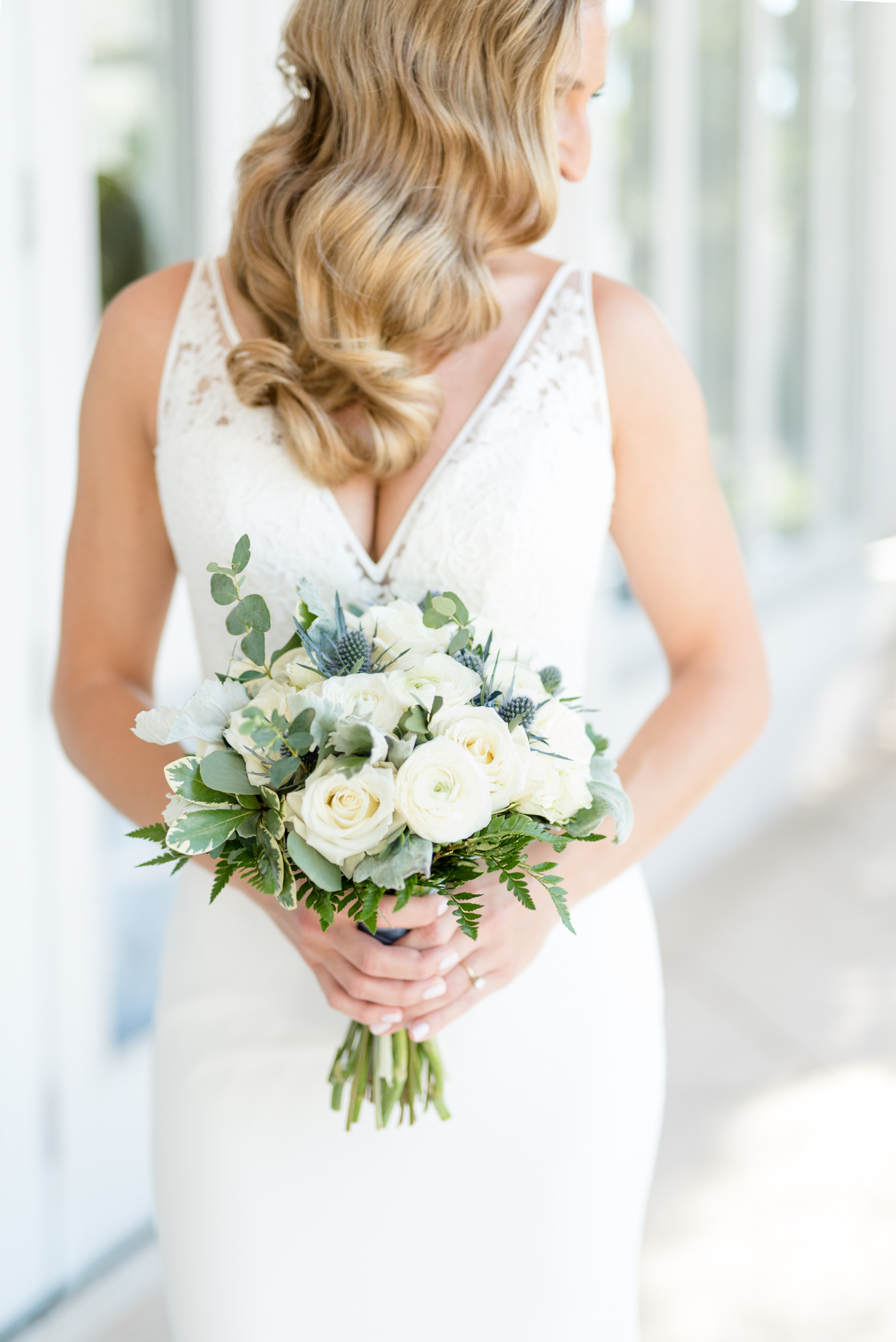 Bride holds flowers and looks over shoulder.