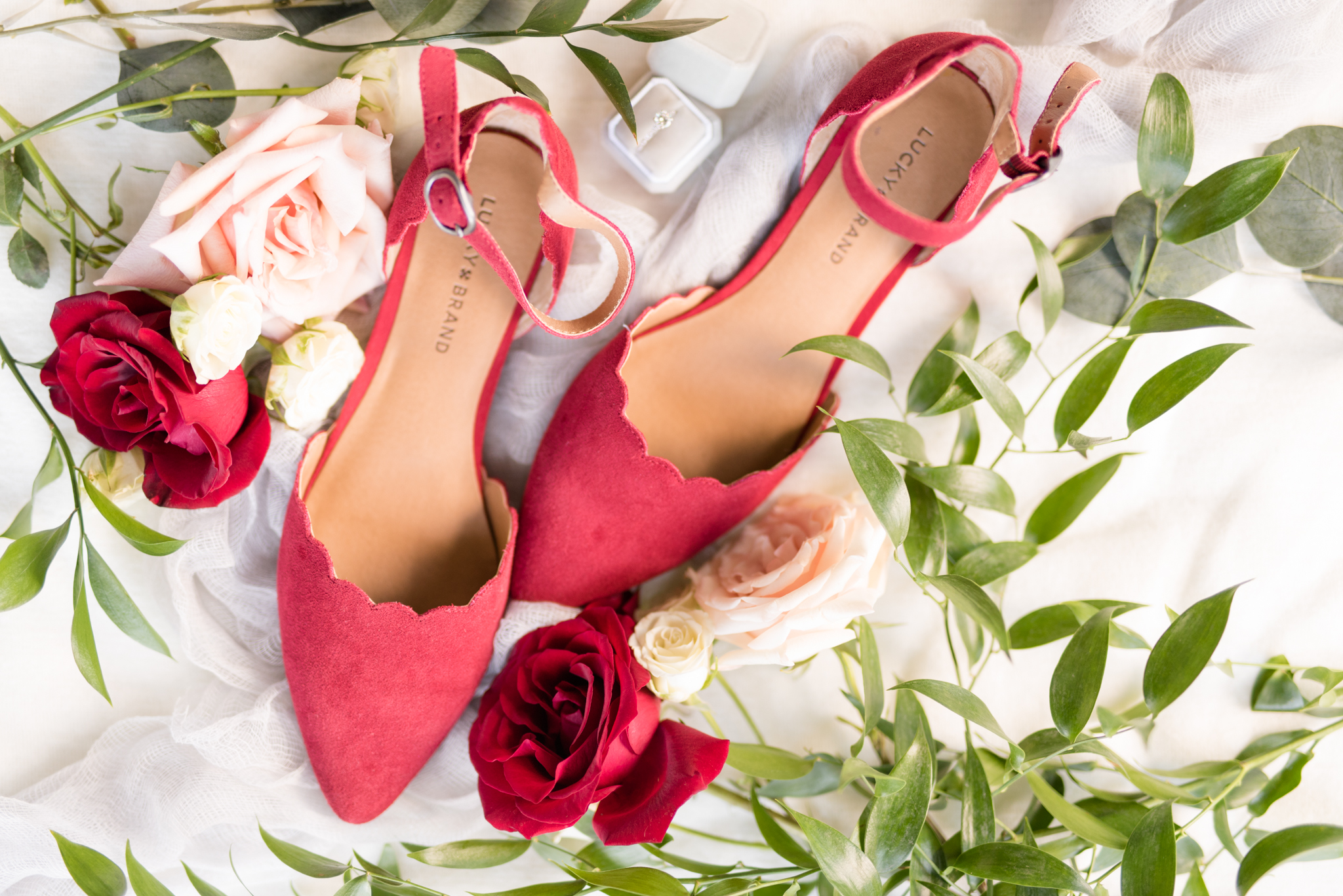 Bridal shoes sit with greenery and flowers.