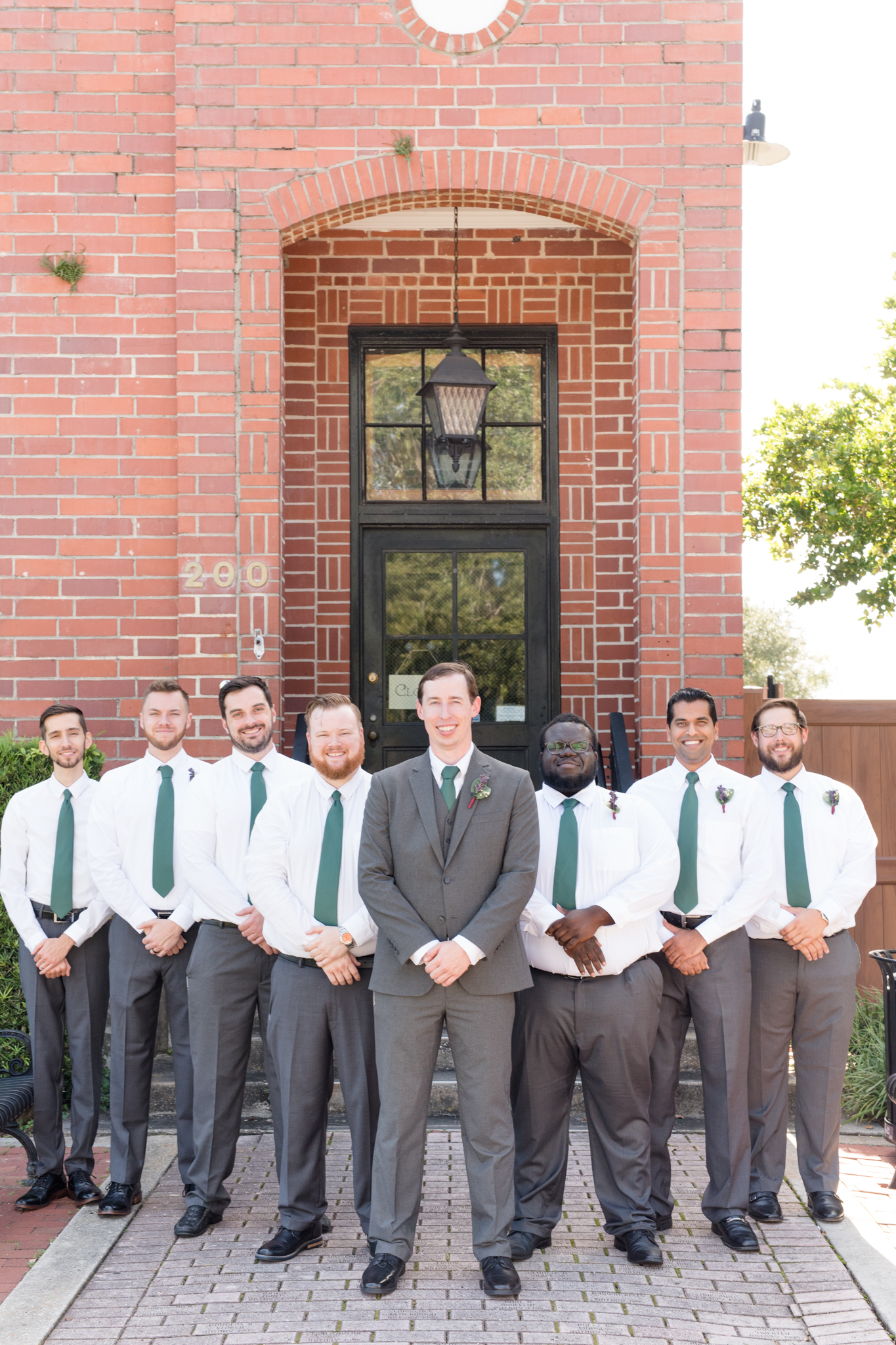 Groom and groomsmen stand together in front of venue.
