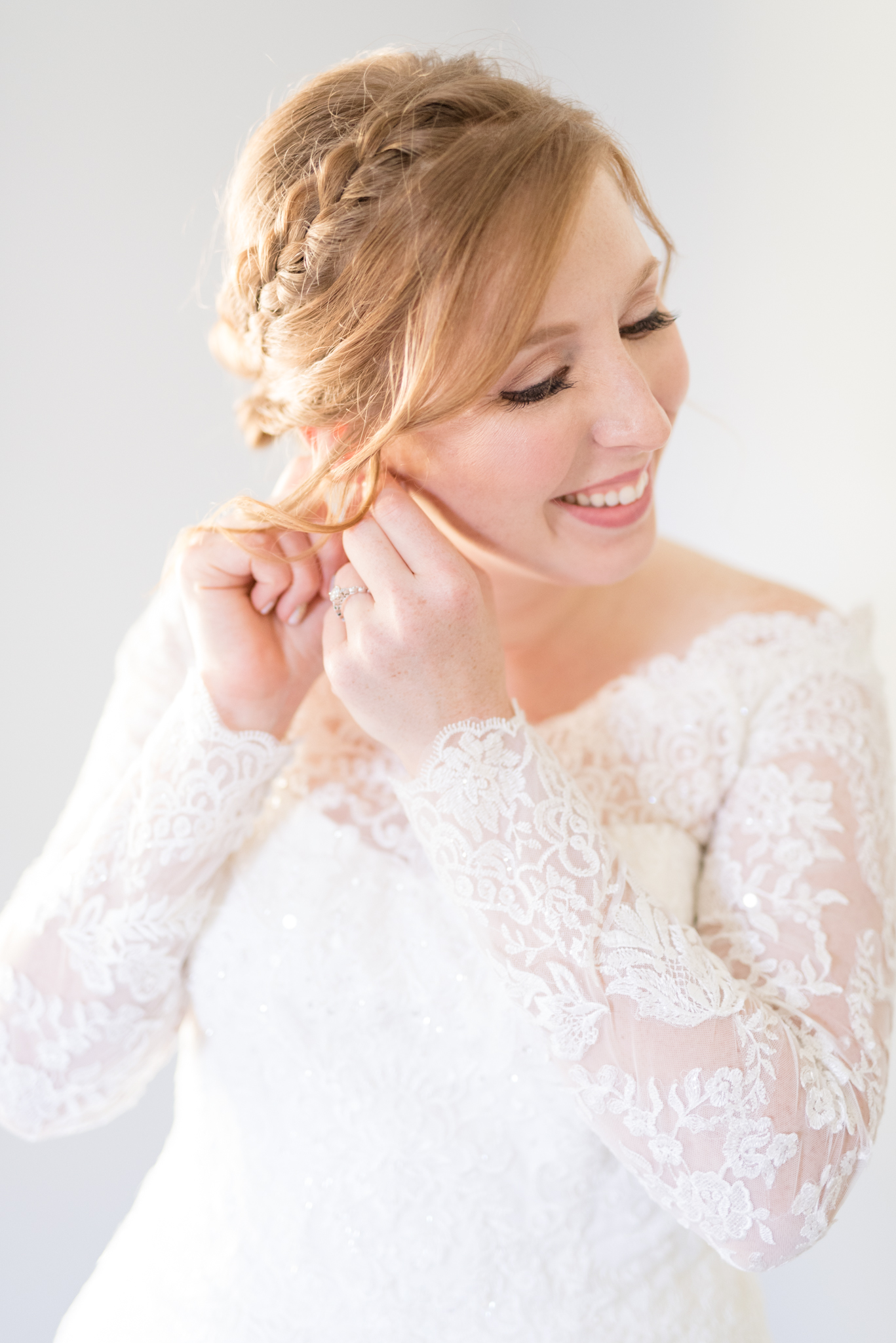 Bride puts on earrings in bridal suite.