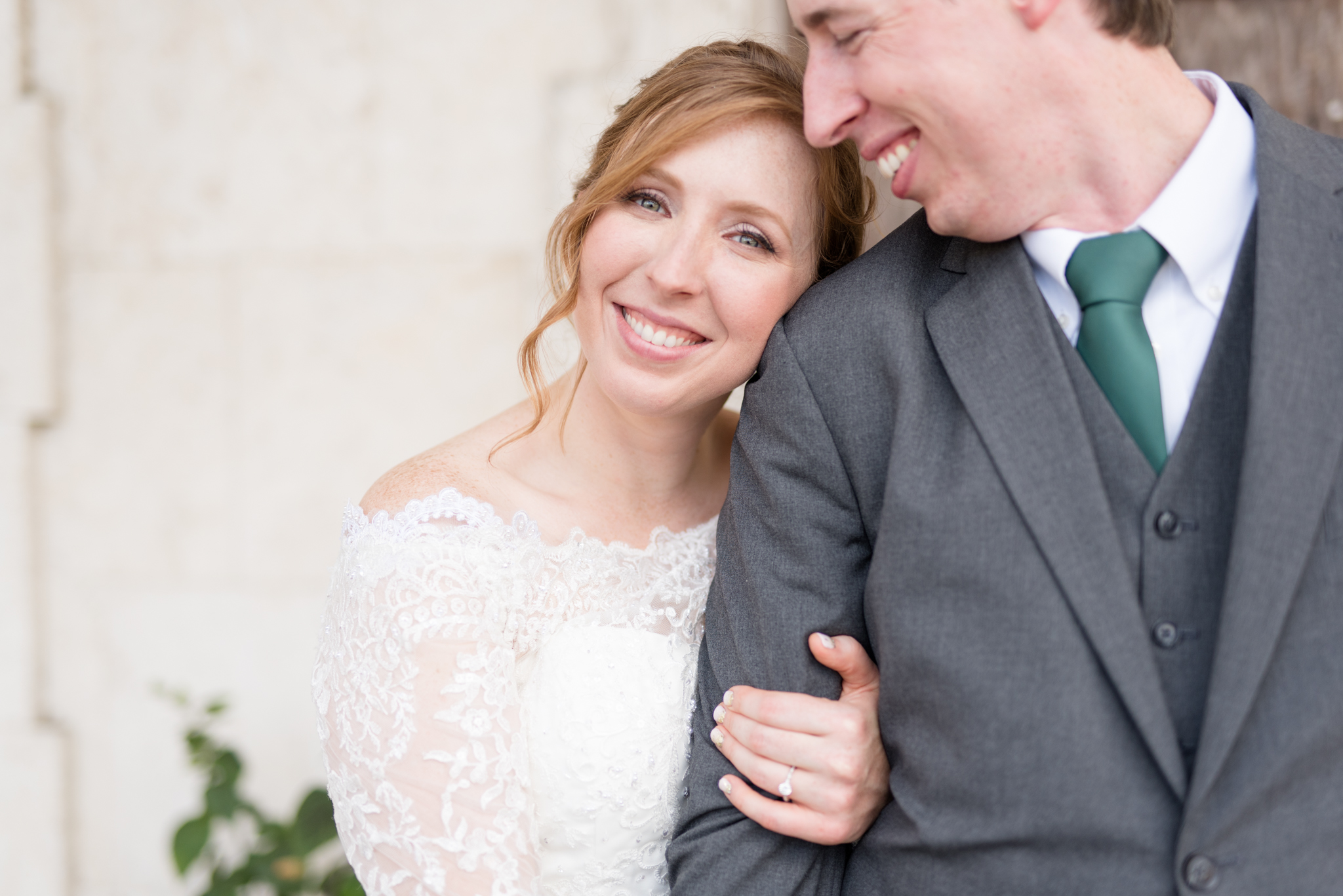 Bride leans head against grooms shoulder and smiles.
