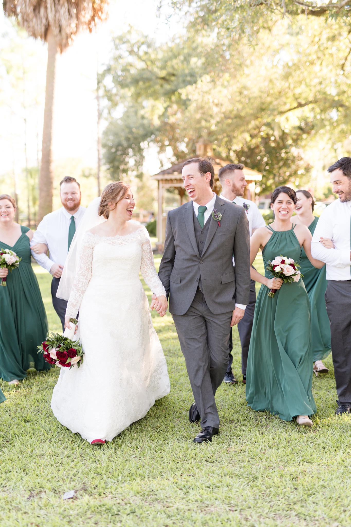 Bride and groom walk and laugh with wedding party.