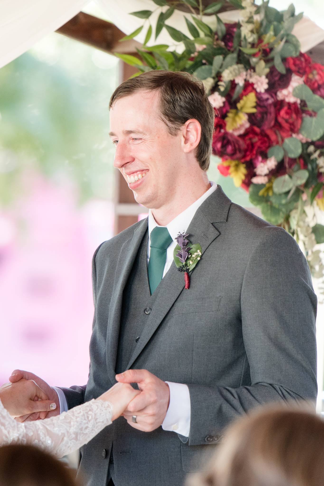 Groom smiles at bride during wedding.
