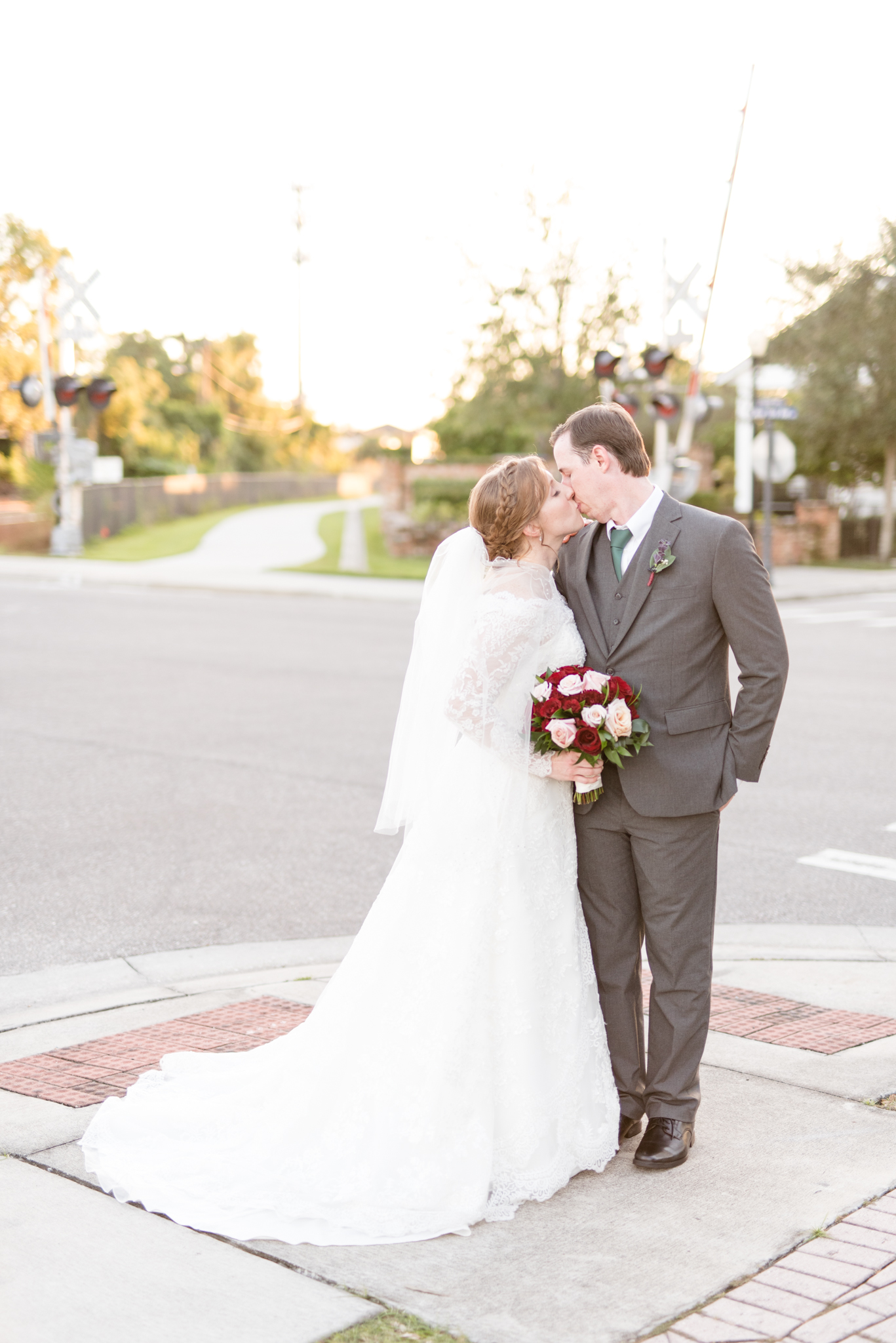 Bride and groom kiss at intersection during sunset.