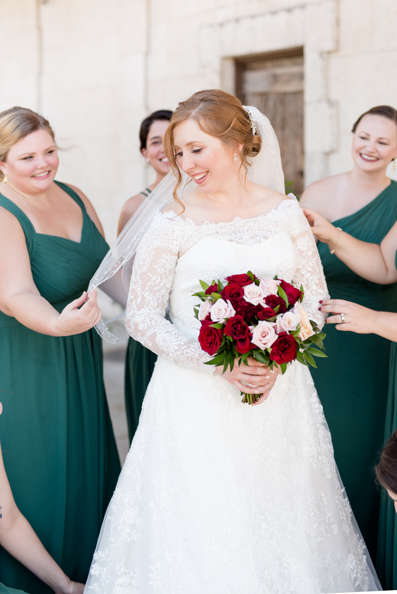 Bride gets help from bridesmaids while getting ready.