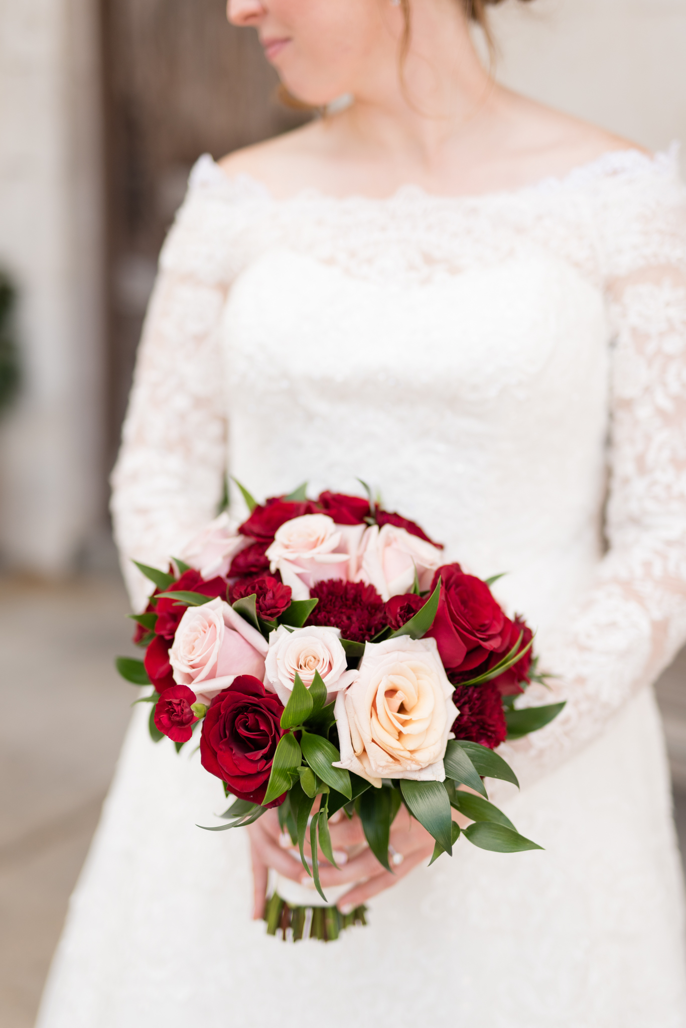 Bride holds wedding bouquet in front of her.