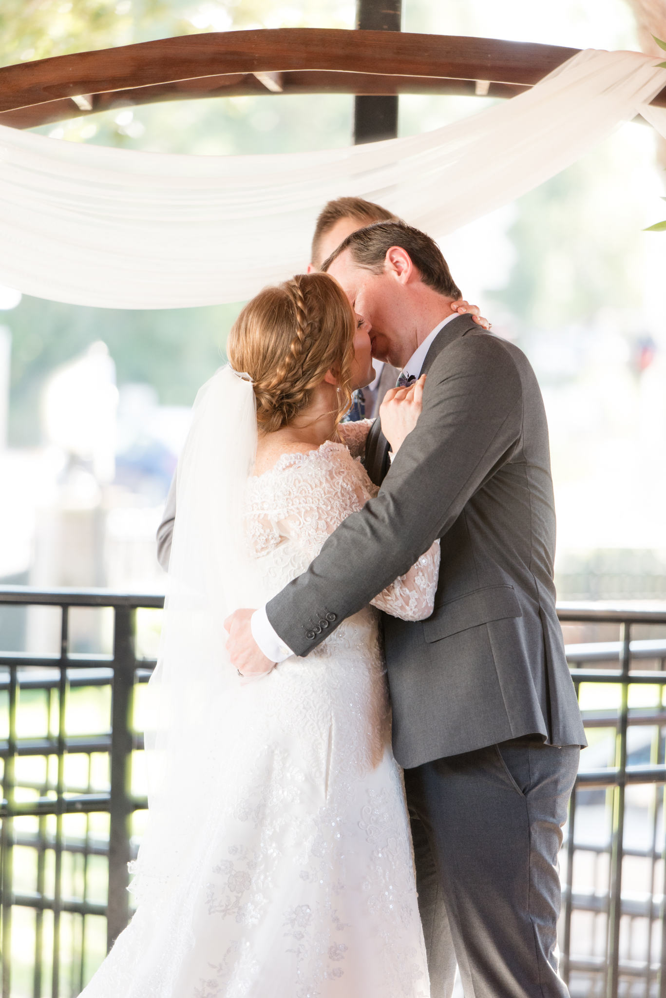 Bride and groom kiss during wedding ceremony.