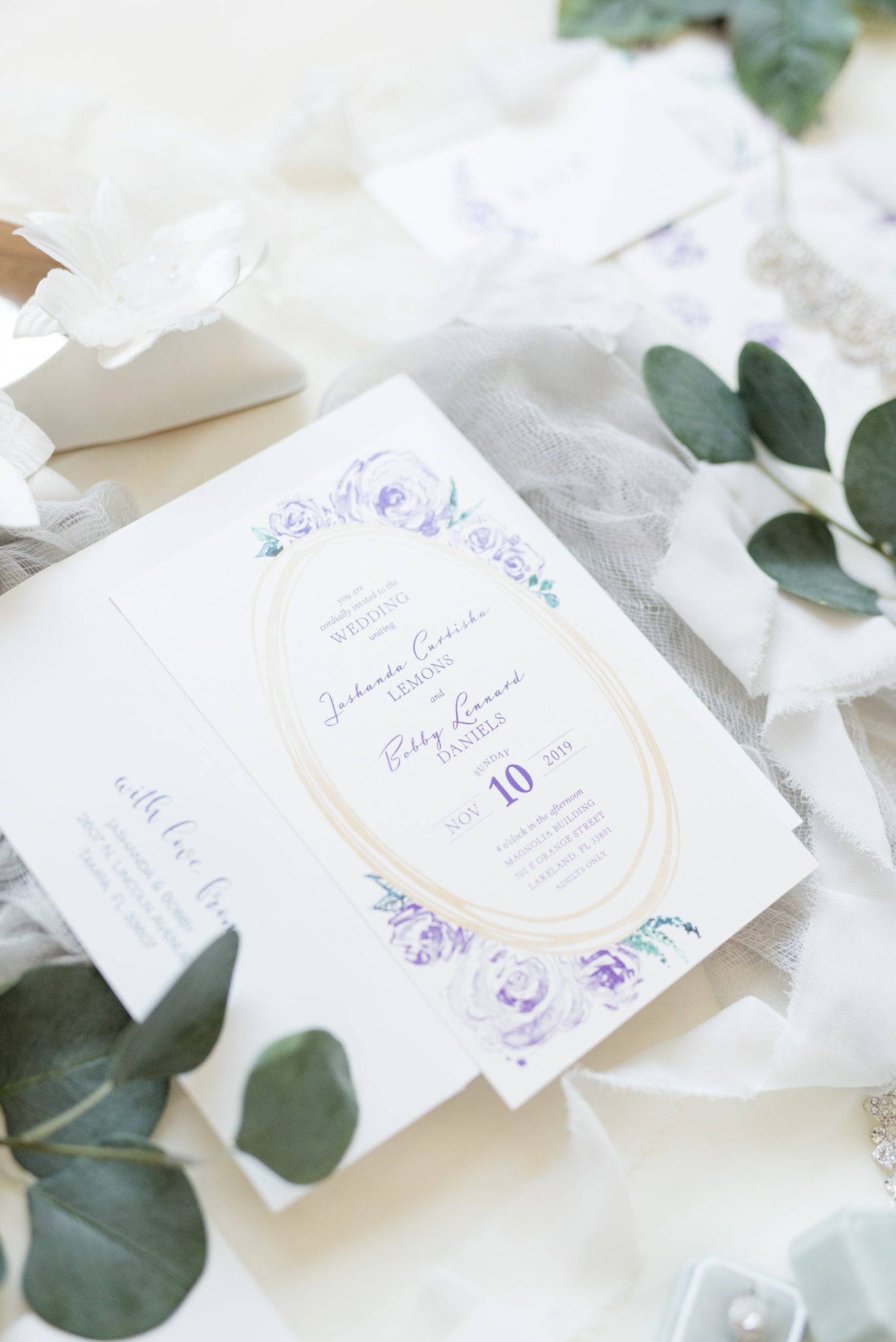 Wedding invitation sits with ribbon and florals.