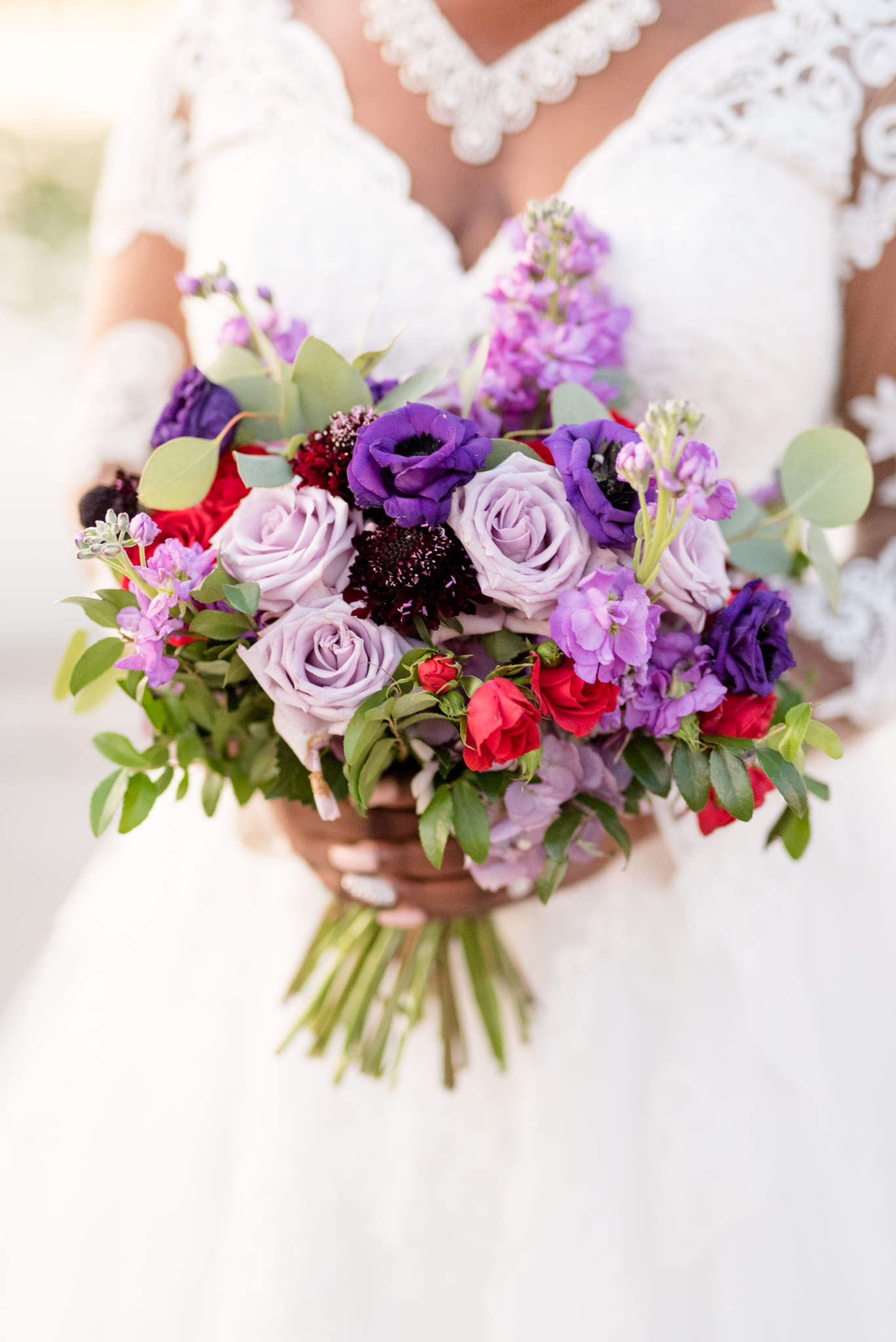Bride holds purple wedding flowers.