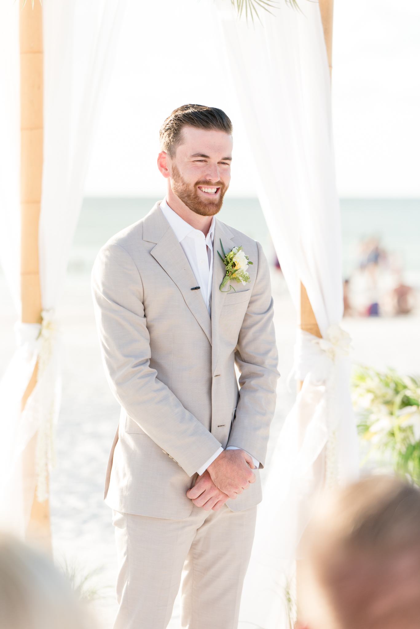 Groom smiles as bride walks down aisle.