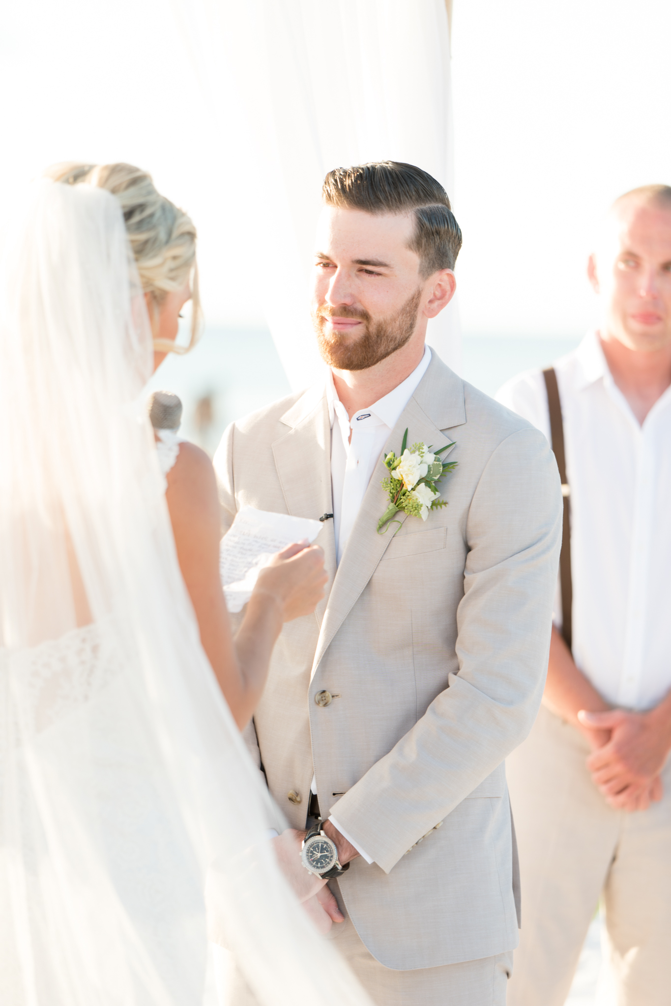 Groom smiles at bride during ceremony.