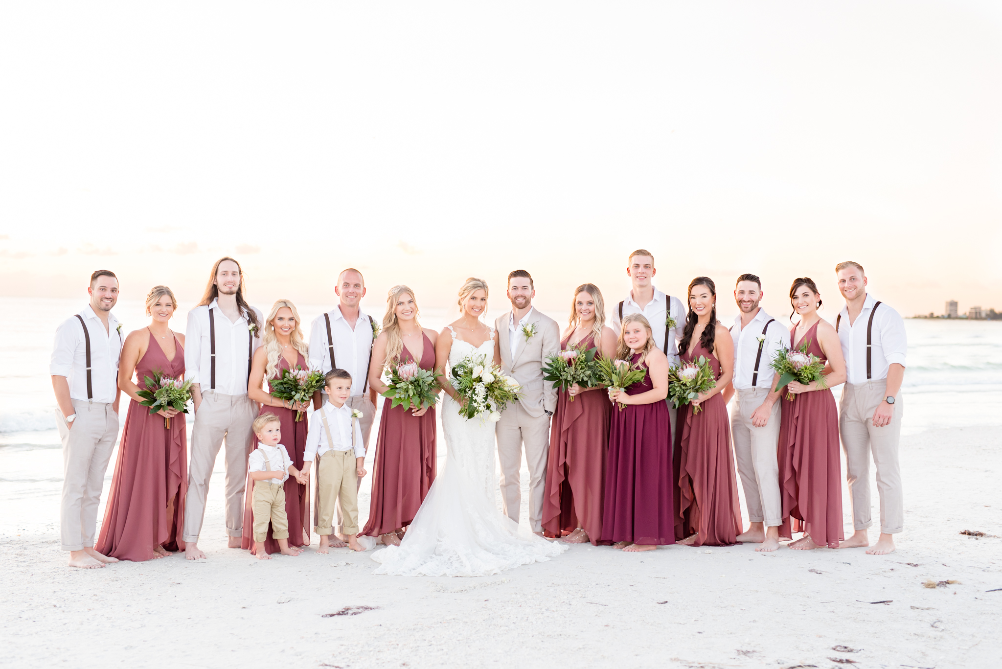 Wedding party smiles at camera at sunset.