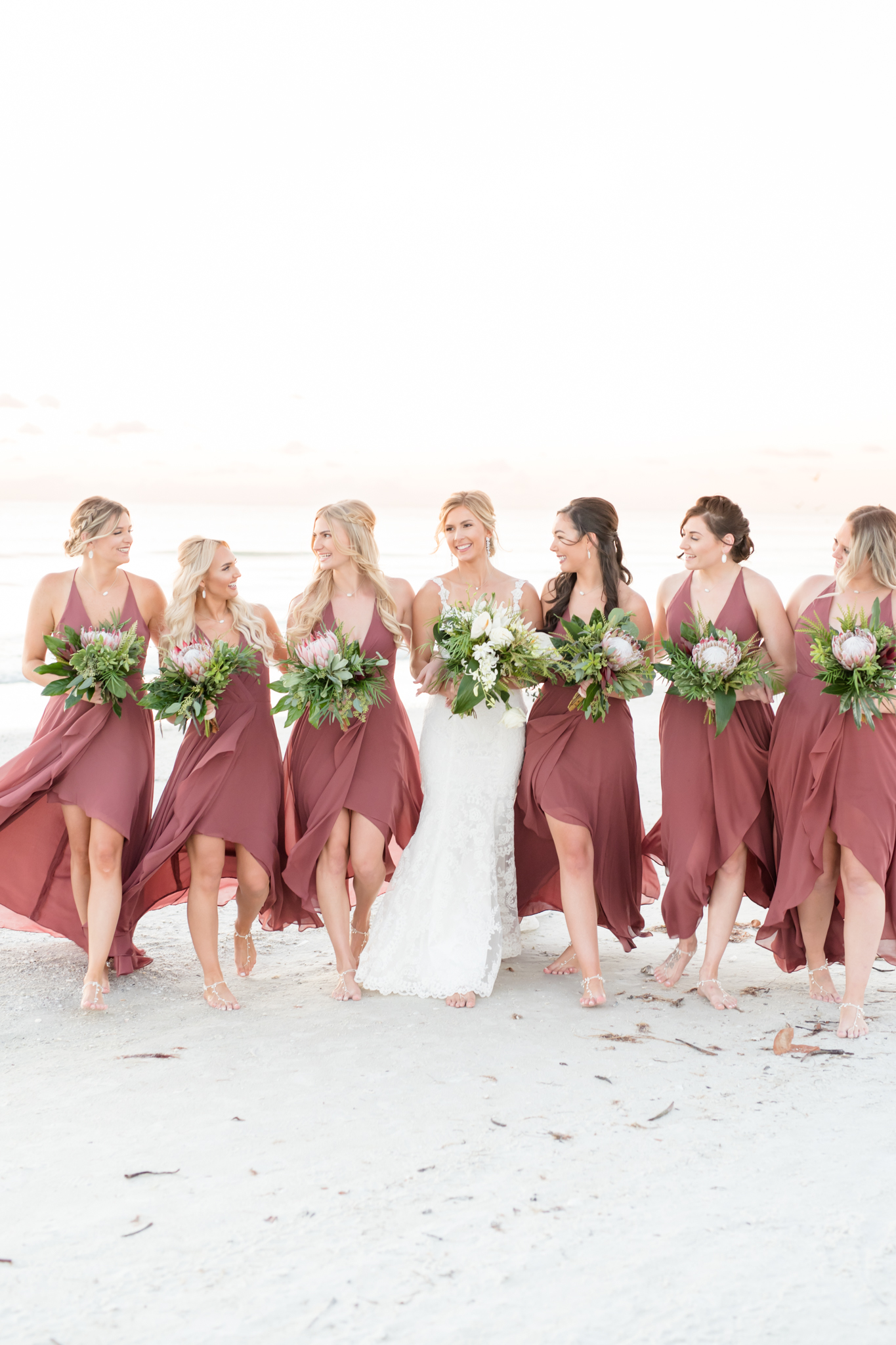 Bride and bridesmaids walk together and laugh.