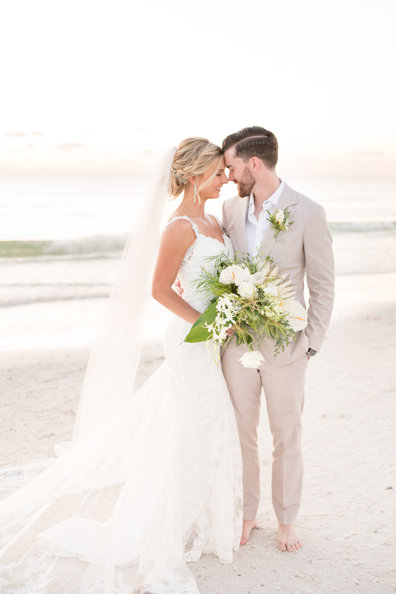 Bride and groom cuddle on the beach.