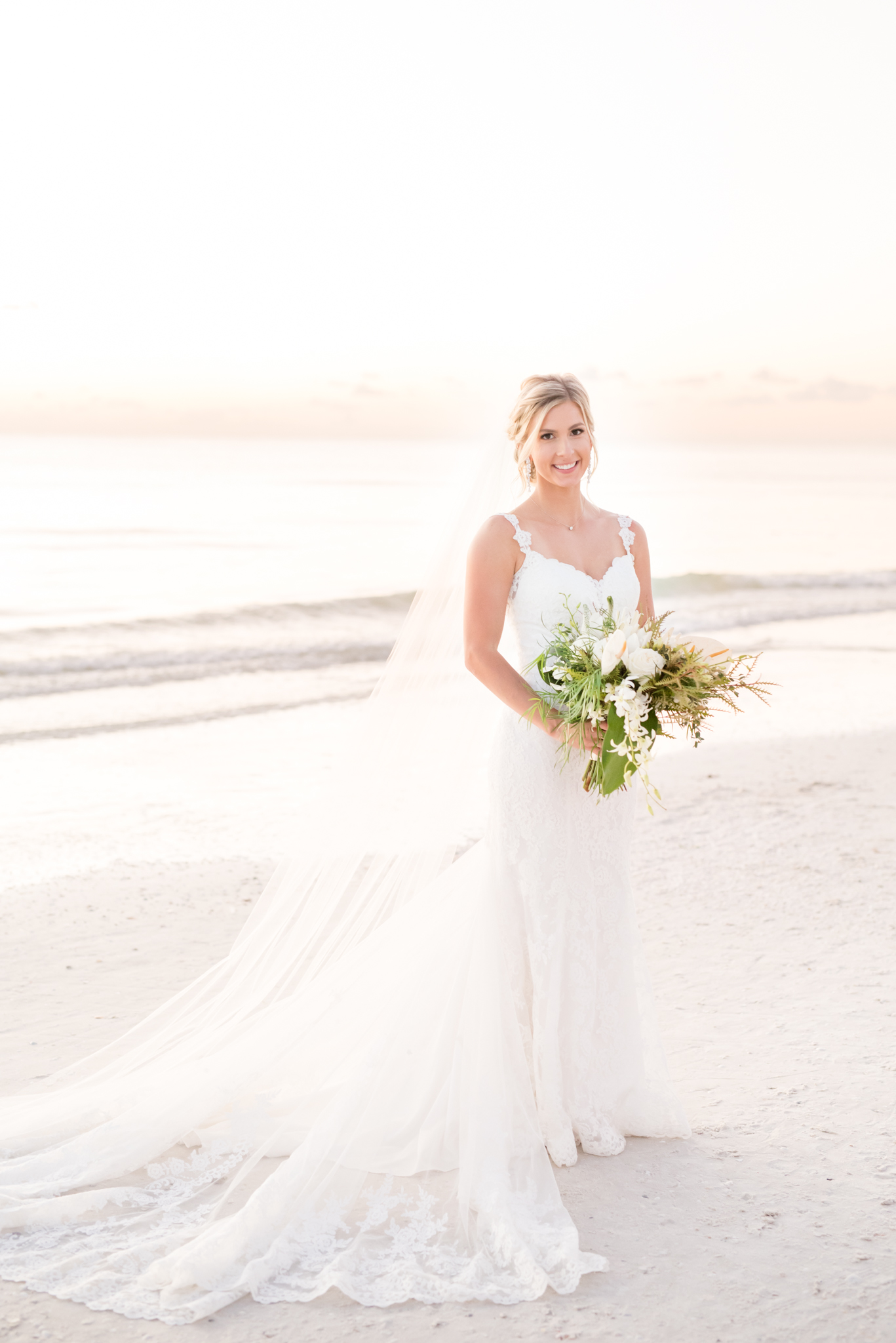 Bride poses and smiles on beach.