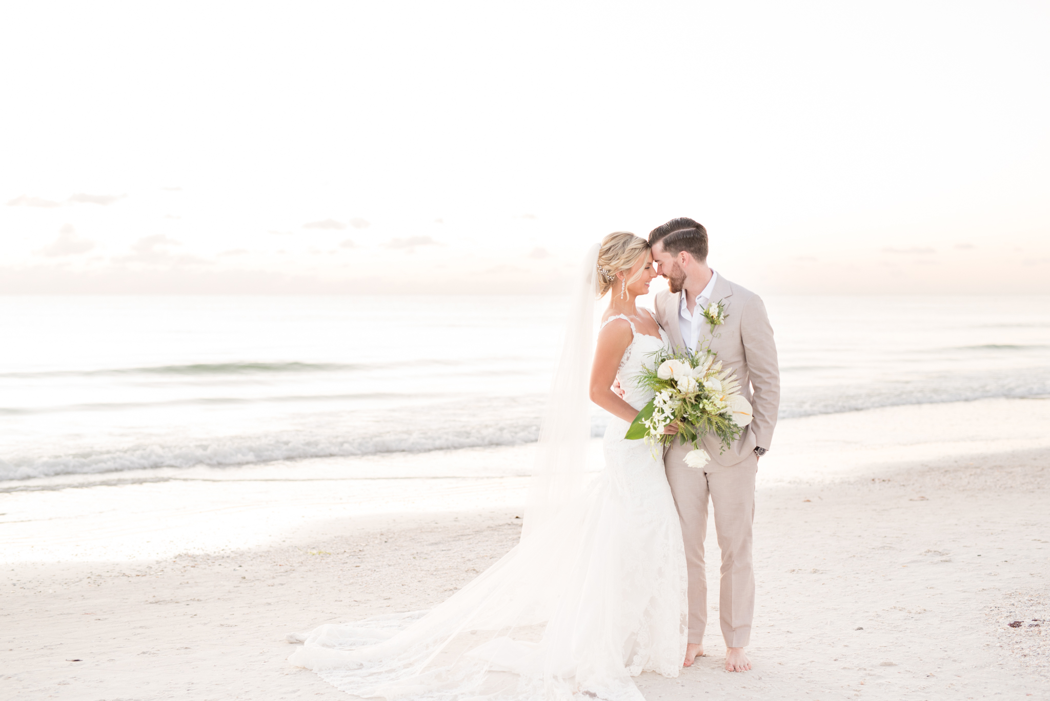 Bride and groom embrace on the beach.
