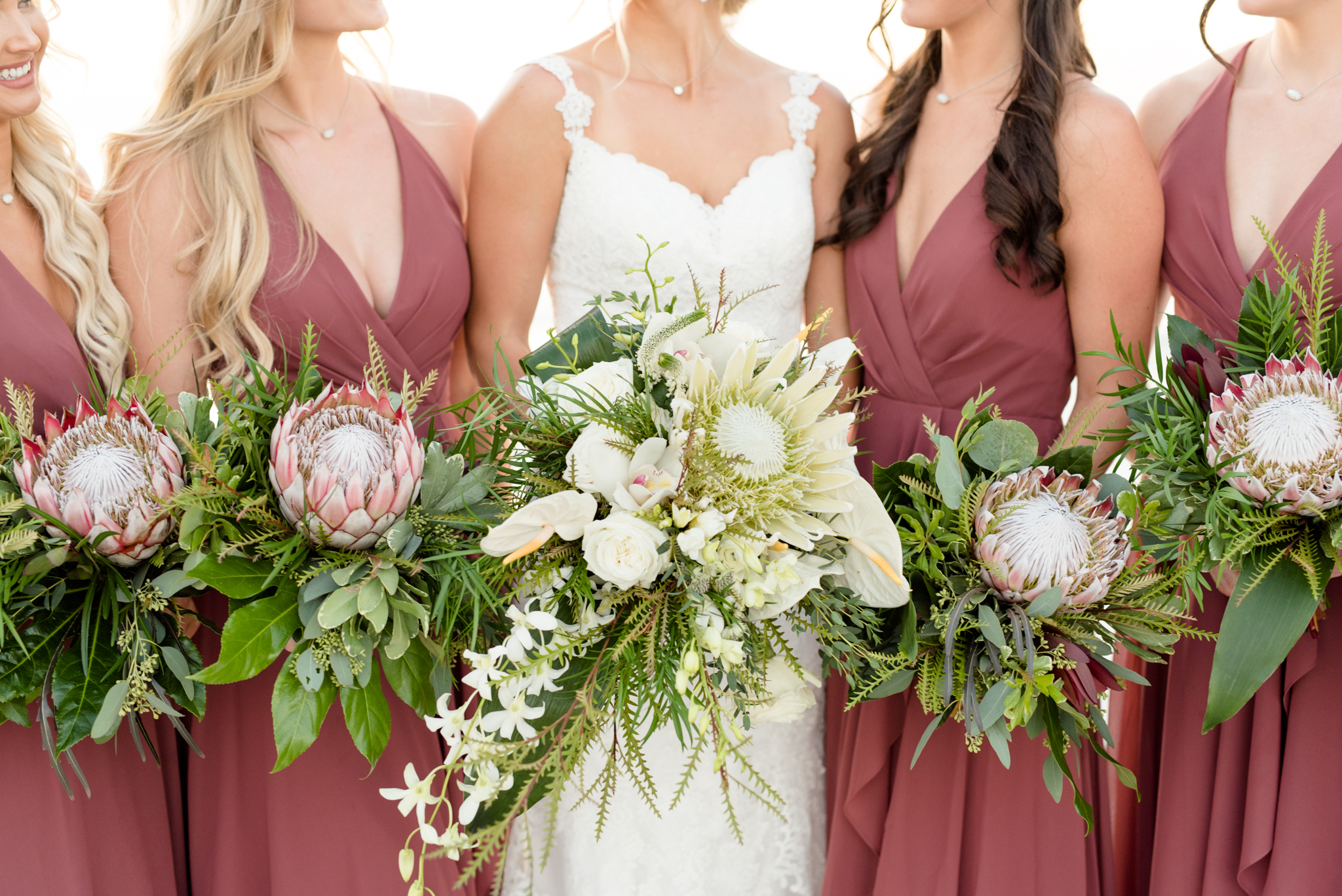 Bridal party holds tropical flowers.