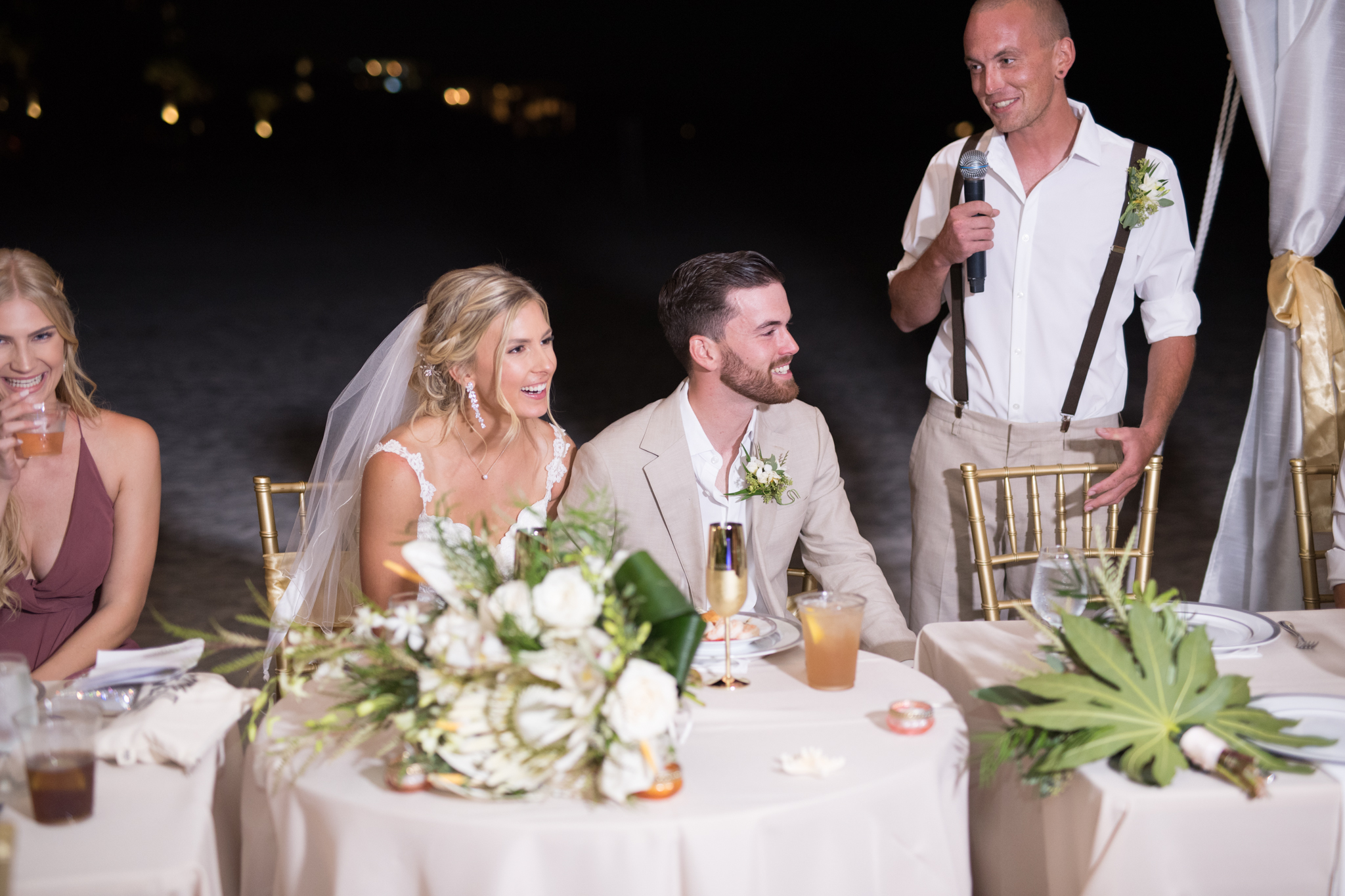 Bride and groom laugh during best man's speech.