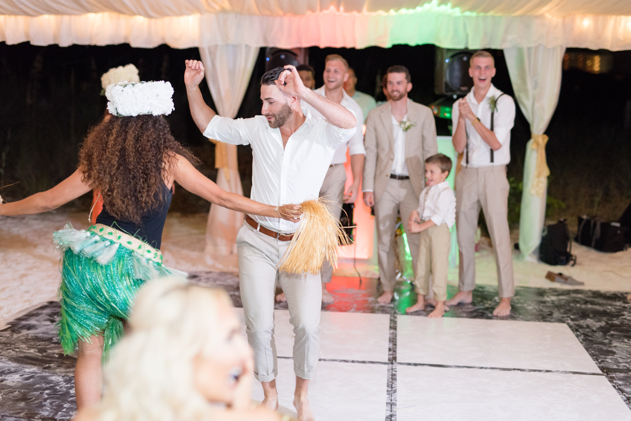 Groomsmen dance with hula girls.