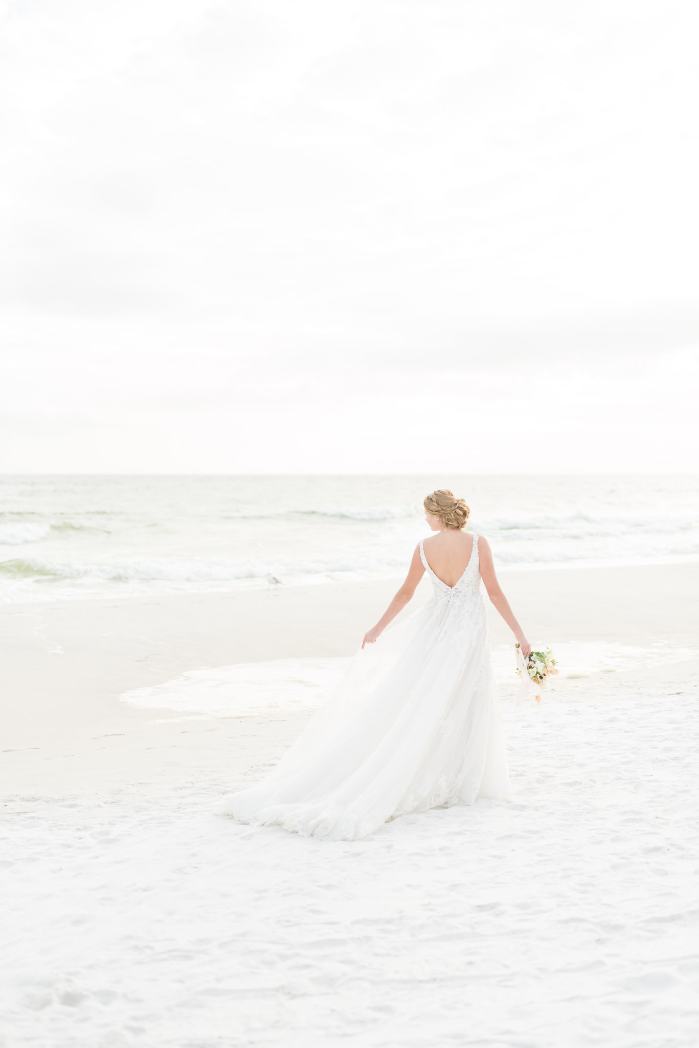 Bride walks across beach.